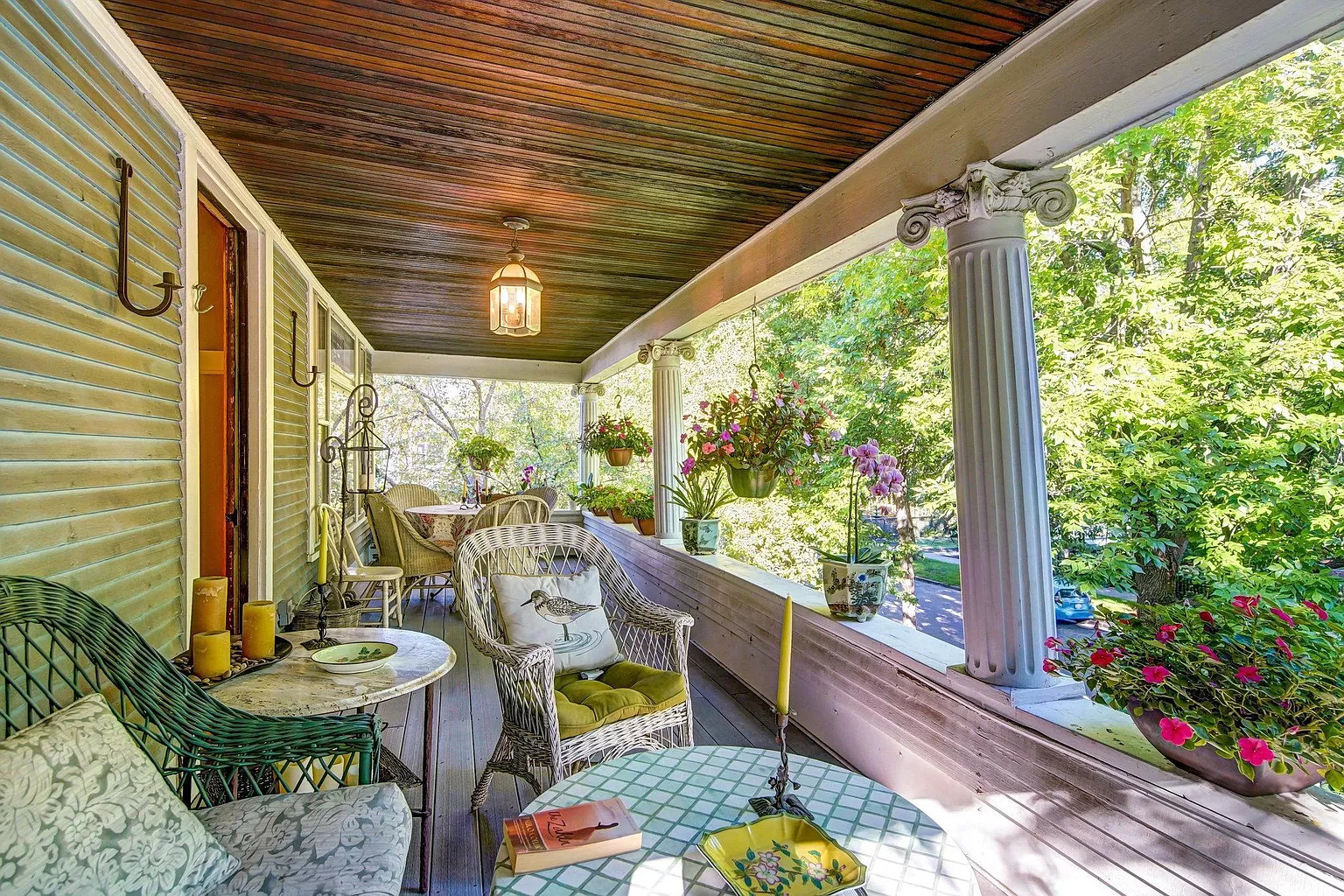 A cozy front porch filled with wicker furniture and vibrant flowers, perfect for relaxation.