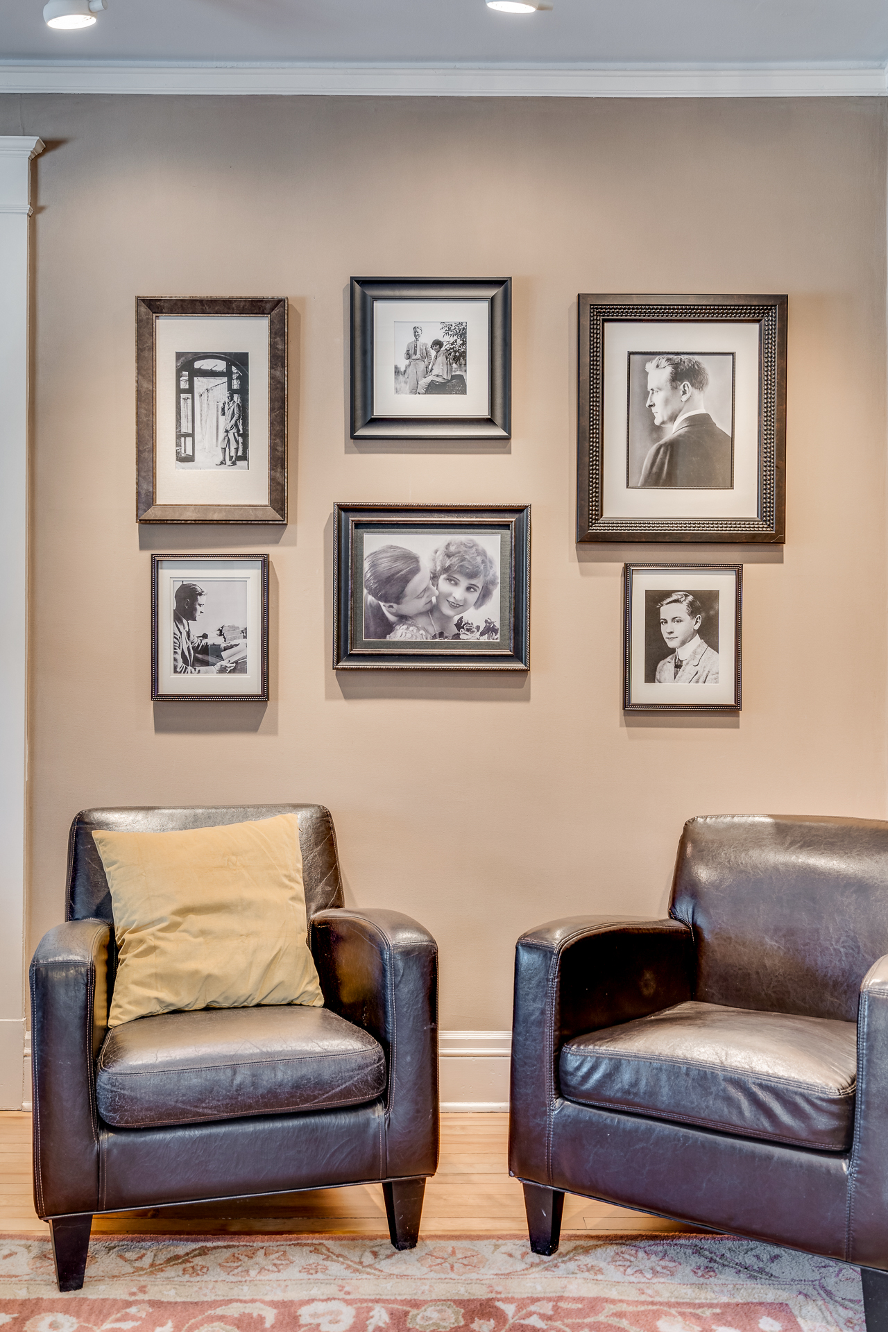 A cozy seating area with leather armchairs and a wall of vintage black and white photographs.
