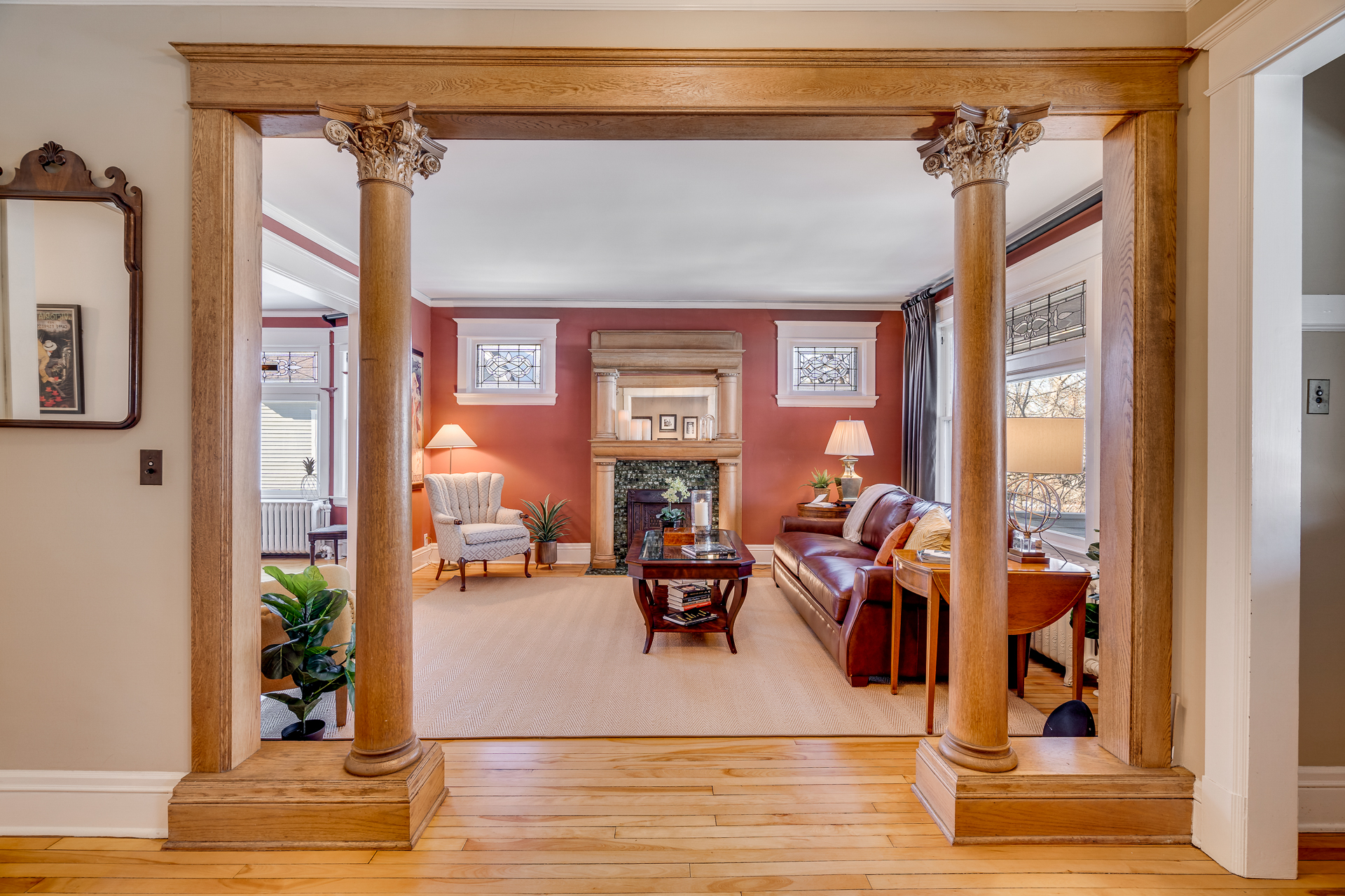 Interior view of a cozy living room with ornate columns, rich red walls, and stylish furniture.