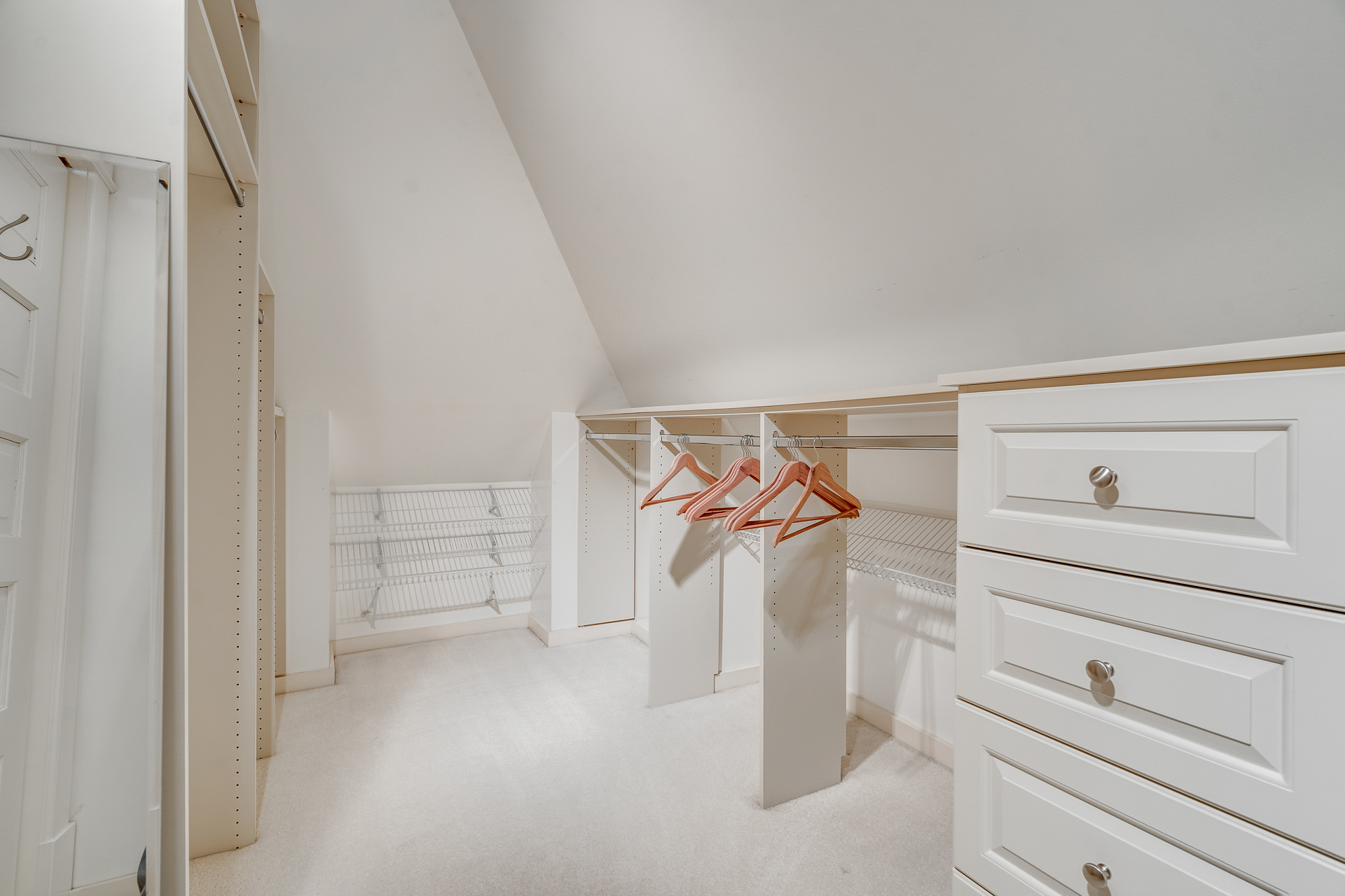 A modern, organized closet with shelves and drawers, featuring wooden hangers.