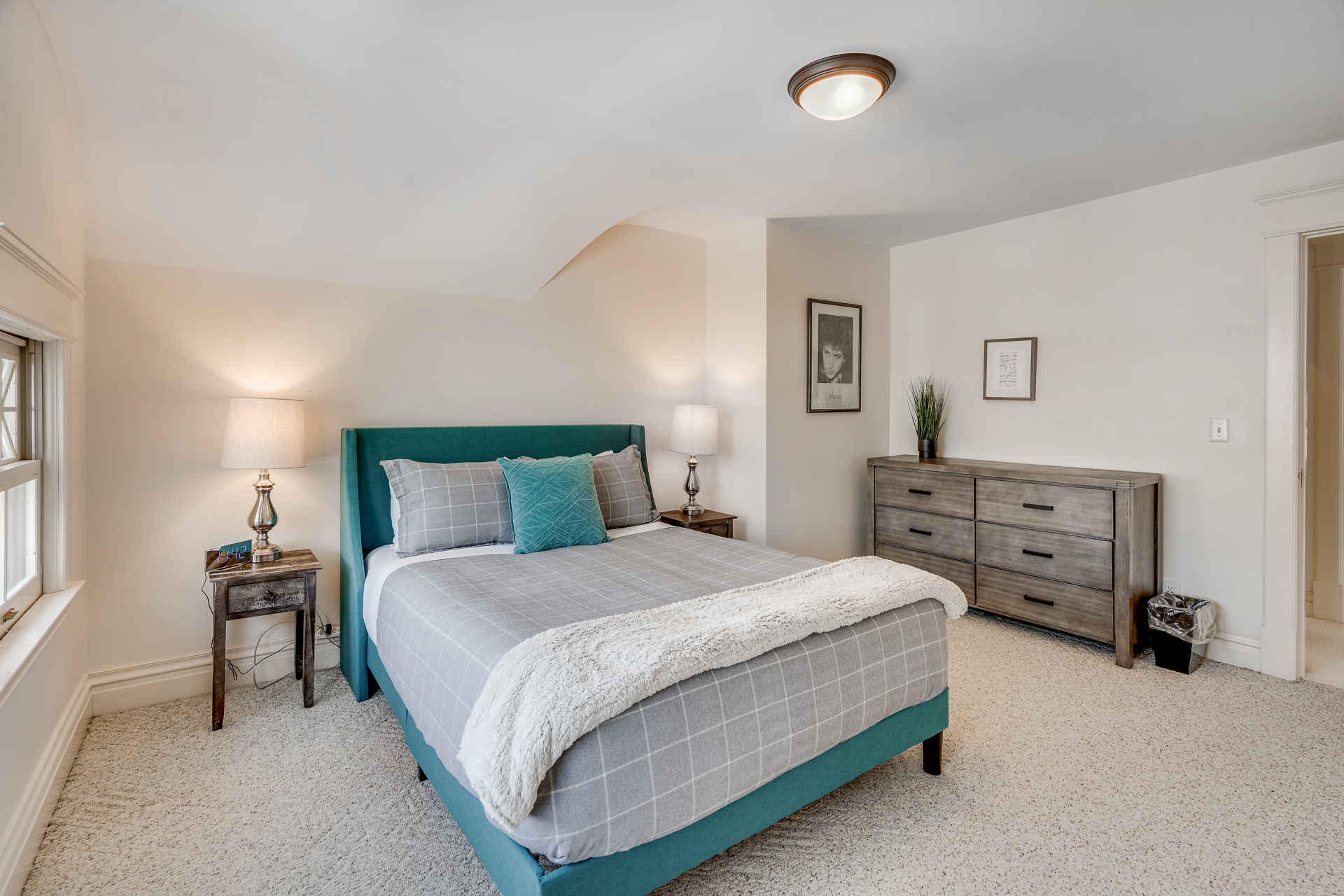 A tranquil bedroom featuring a teal upholstered bed and warm accents.
