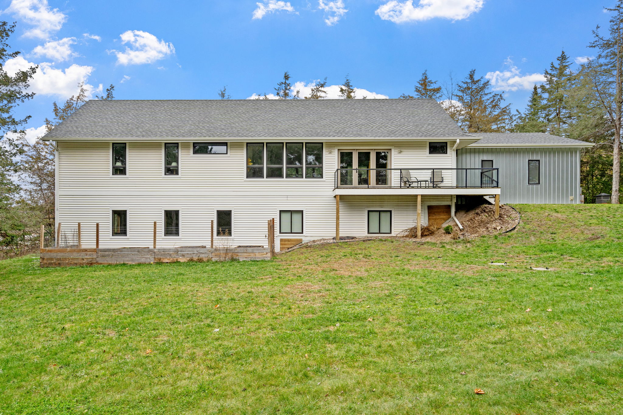 Modern two-story house with a spacious lawn and wrap-around deck.