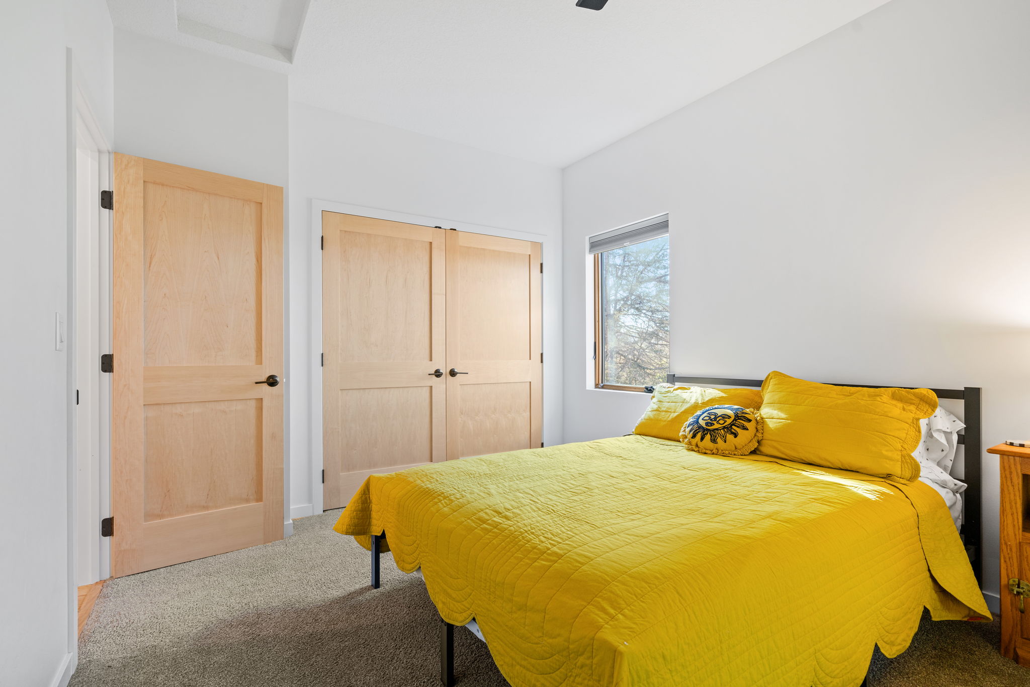 Cozy bedroom with a bright yellow quilt and natural light.