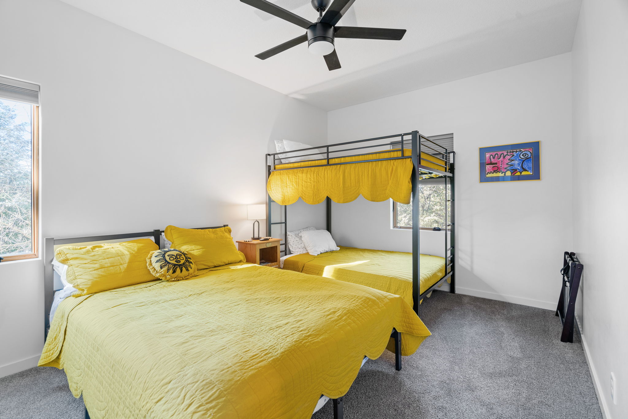 A vibrant yellow-themed bedroom featuring a double bed and a bunk bed, illuminated by natural light.