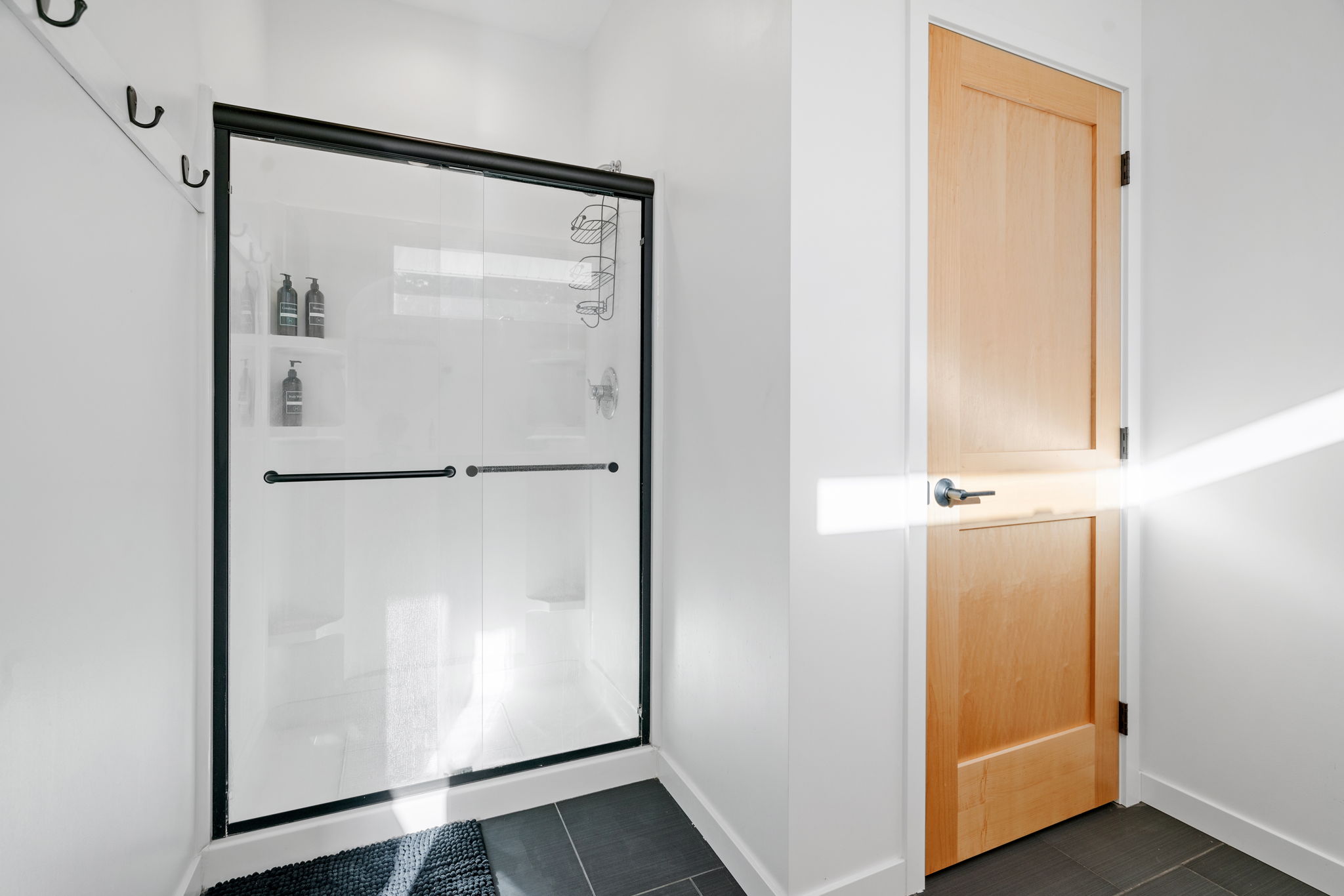 A modern bathroom featuring a sleek glass shower and light wooden door.