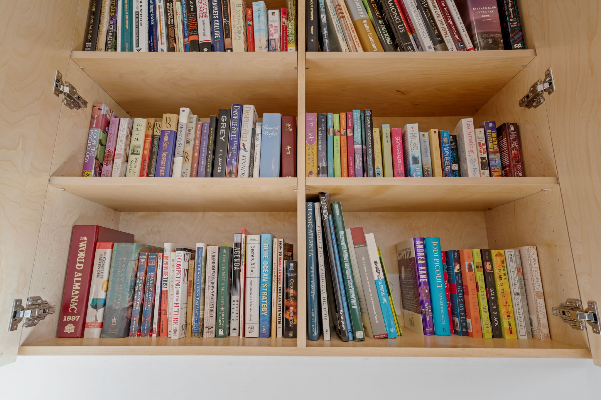 A well-organized wooden bookshelf with a diverse collection of books.
