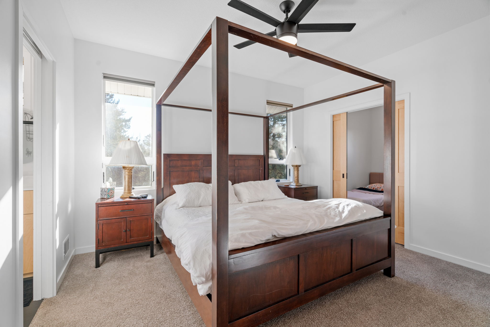 A serene master bedroom with a wooden four-poster bed and natural light.