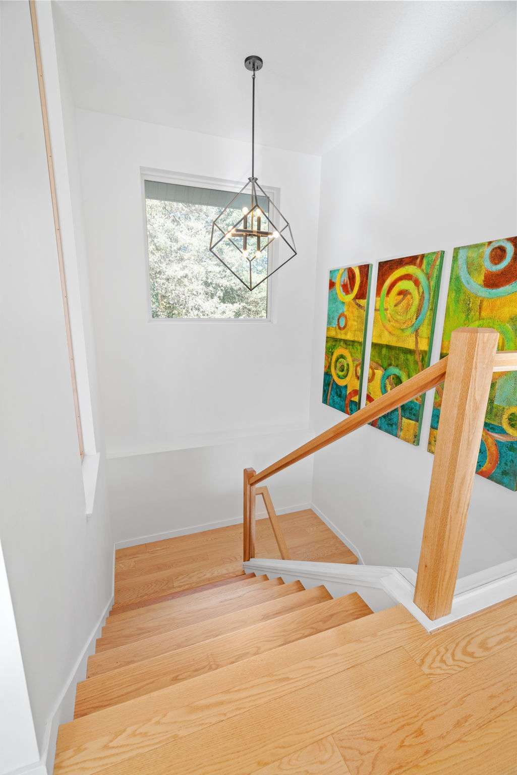 Modern staircase adorned with vibrant artwork and natural light.