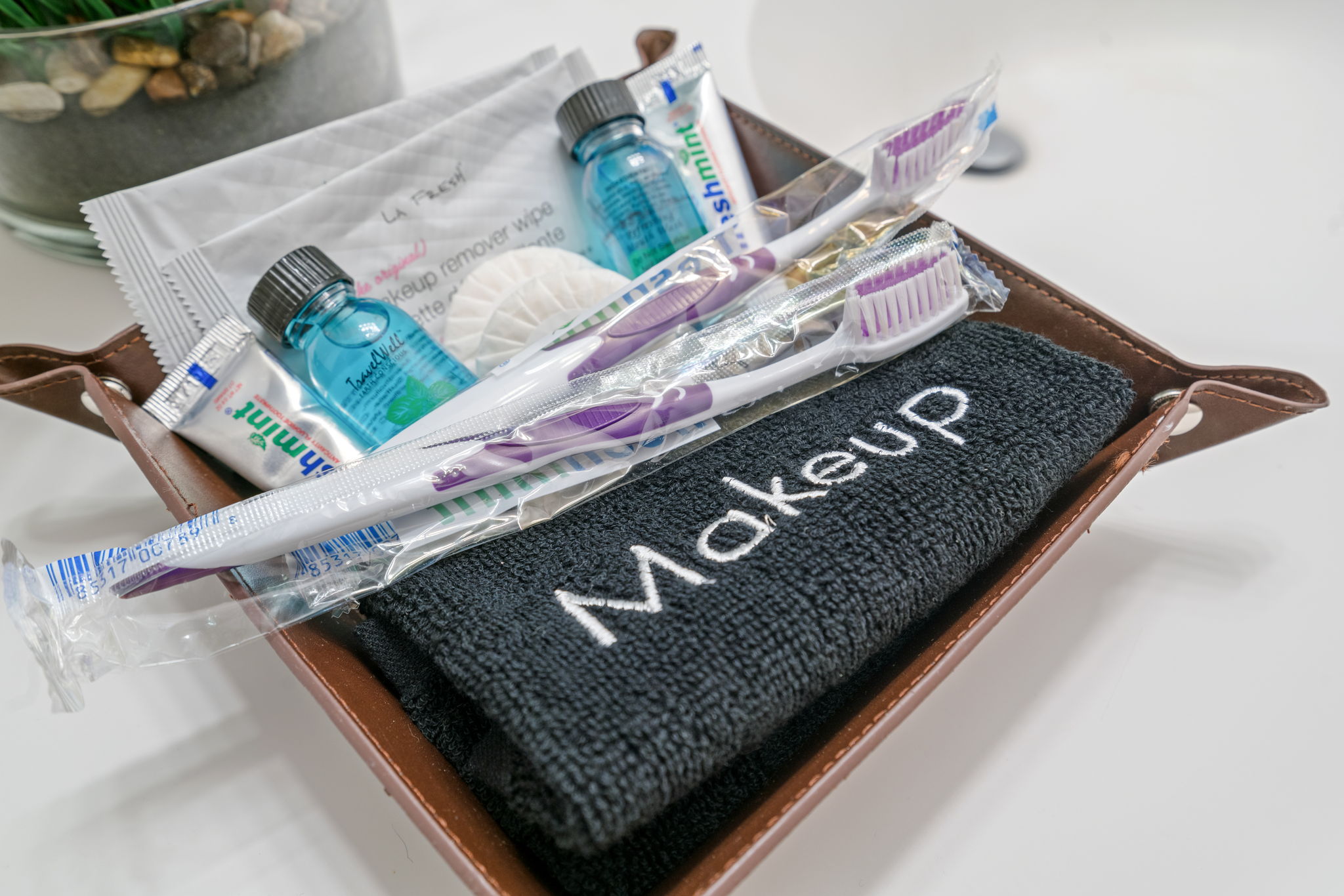 A well-organized toiletries basket featuring a makeup towel, toothbrushes, and personal care items.
