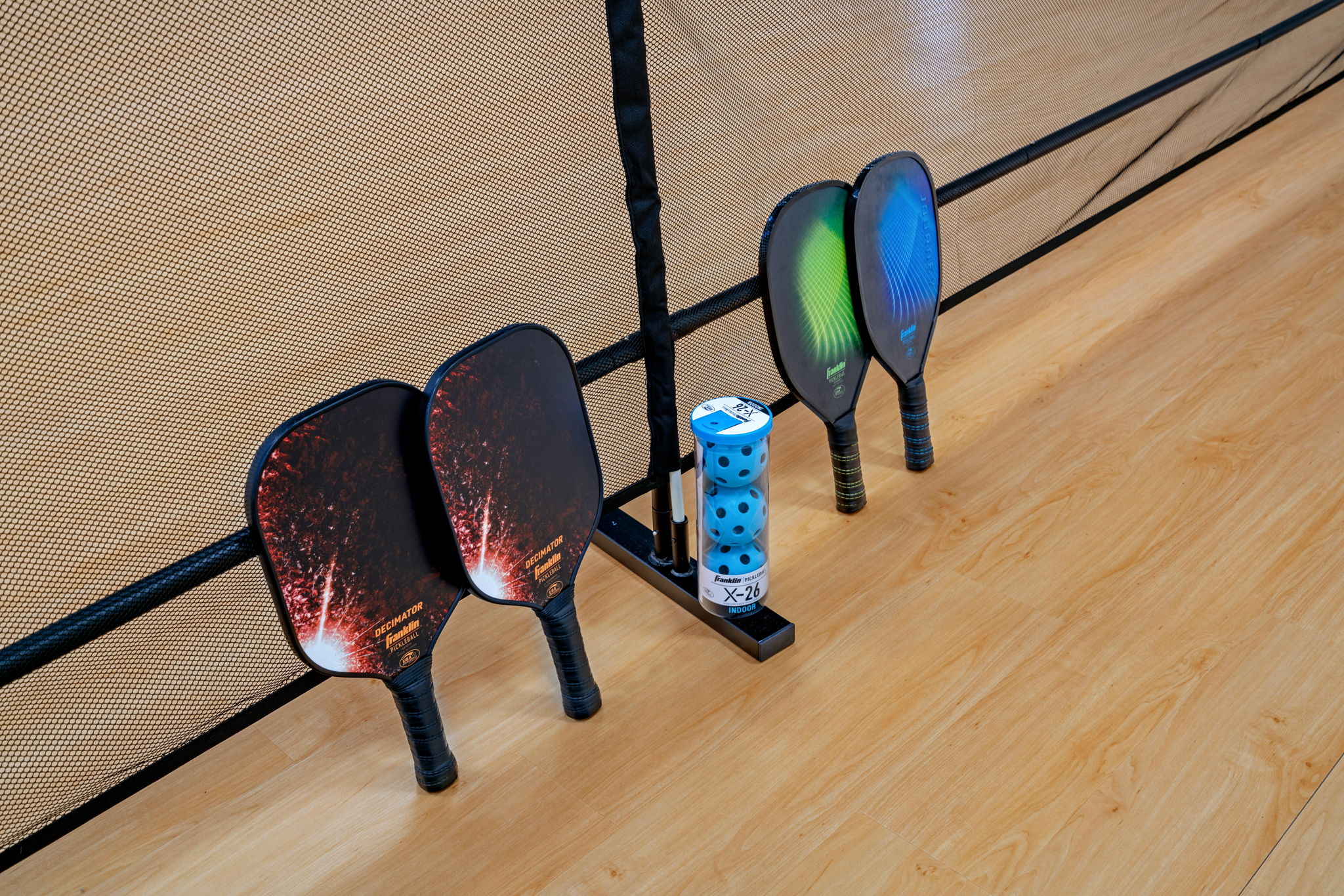 Indoor pickleball paddles and balls arranged neatly against a net.
