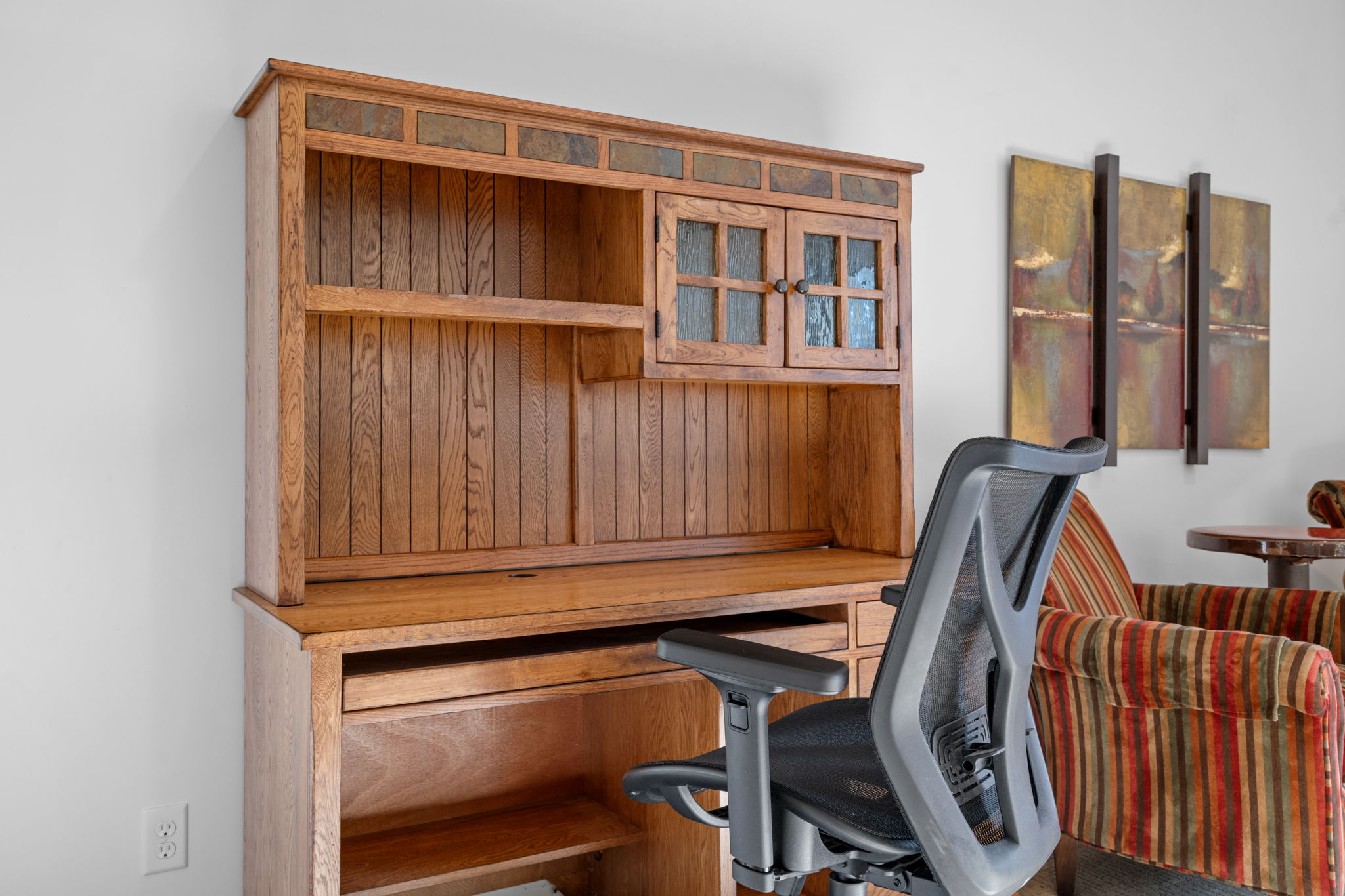 A modern wooden desk hutch paired with an ergonomic chair in a cozy workspace.