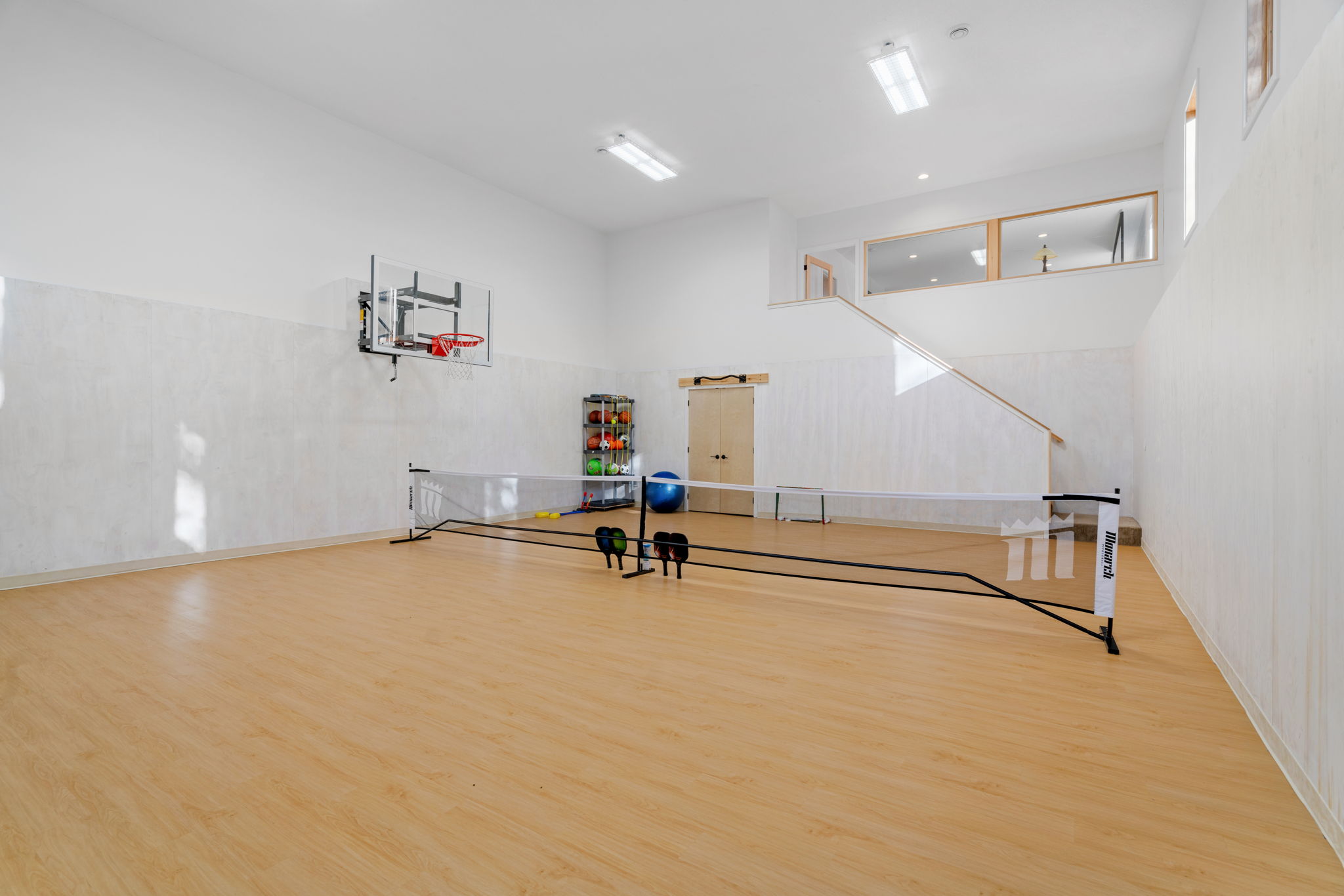 A bright and versatile indoor sports area featuring a basketball hoop and exercise equipment.