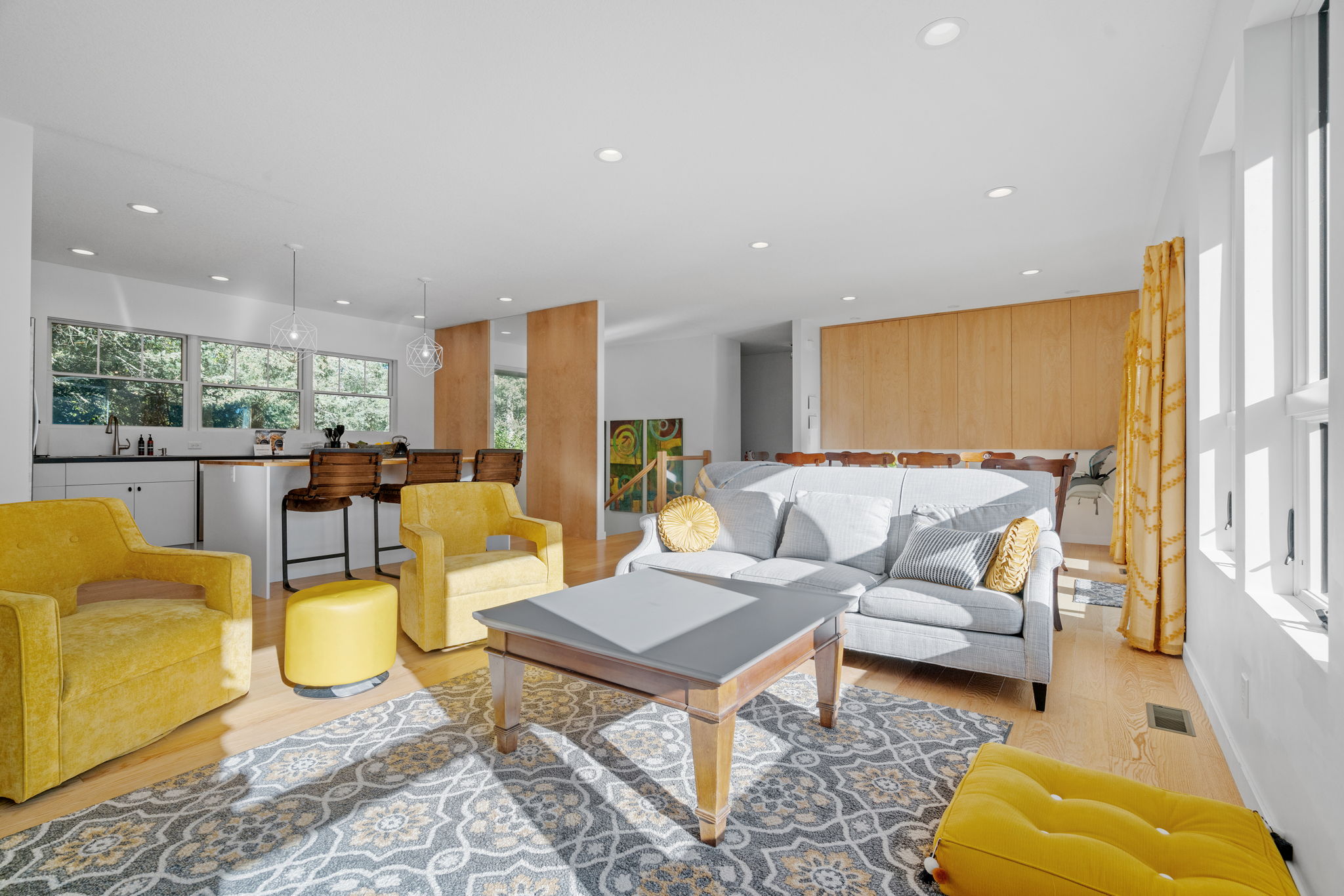 Modern living room with yellow furniture and a sleek kitchen.