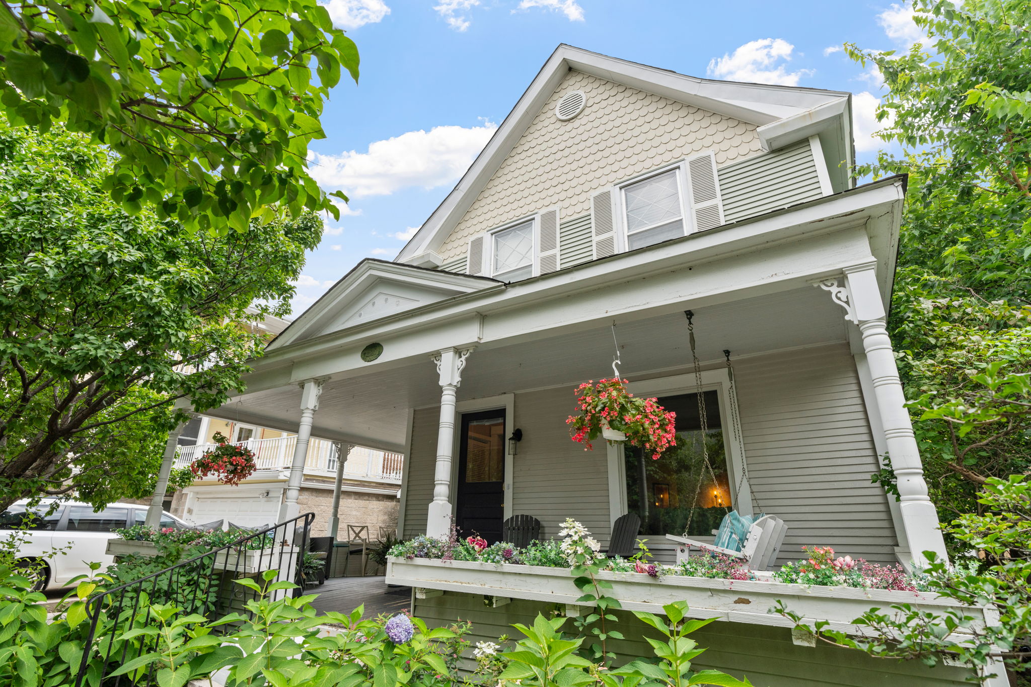 Charming two-story house with a welcoming front porch and colorful flowers.