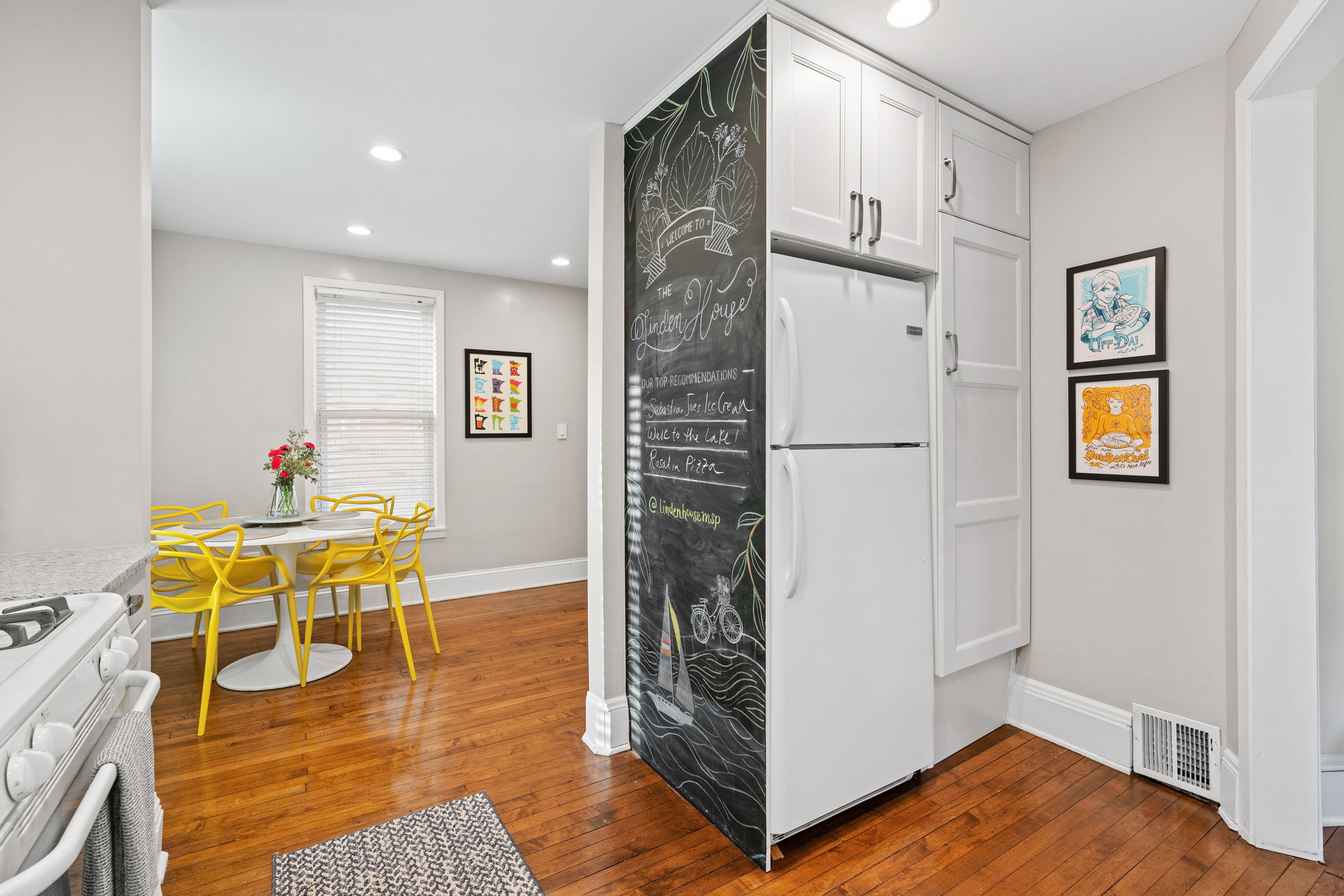 A modern kitchen featuring bright yellow chairs and a chalkboard refrigerator.