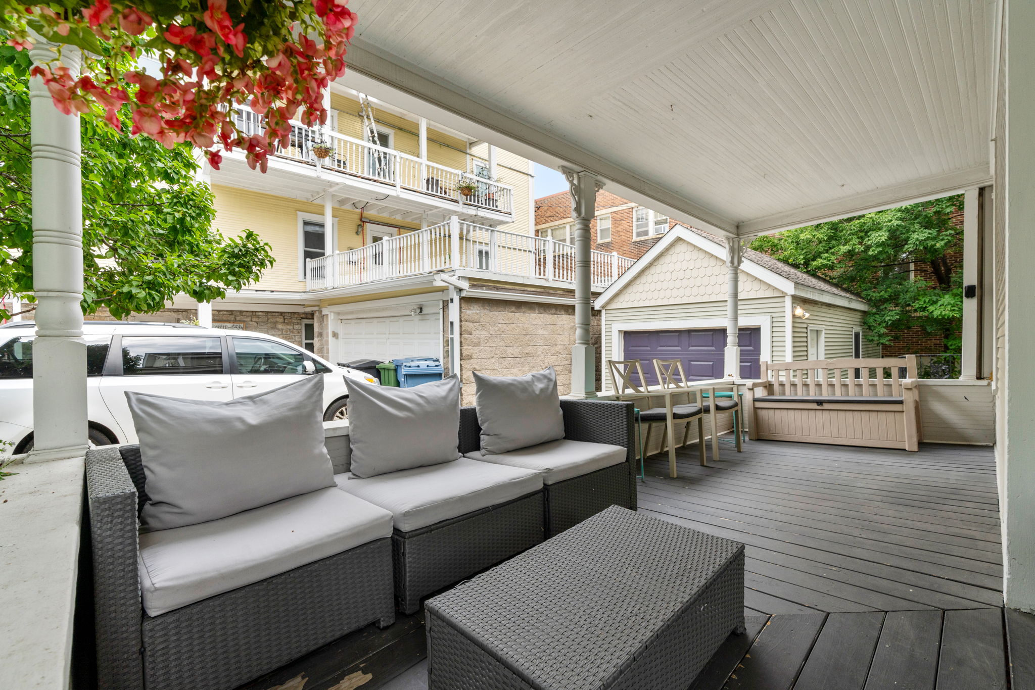 Cozy outdoor patio with sectional sofa and vibrant flowers.