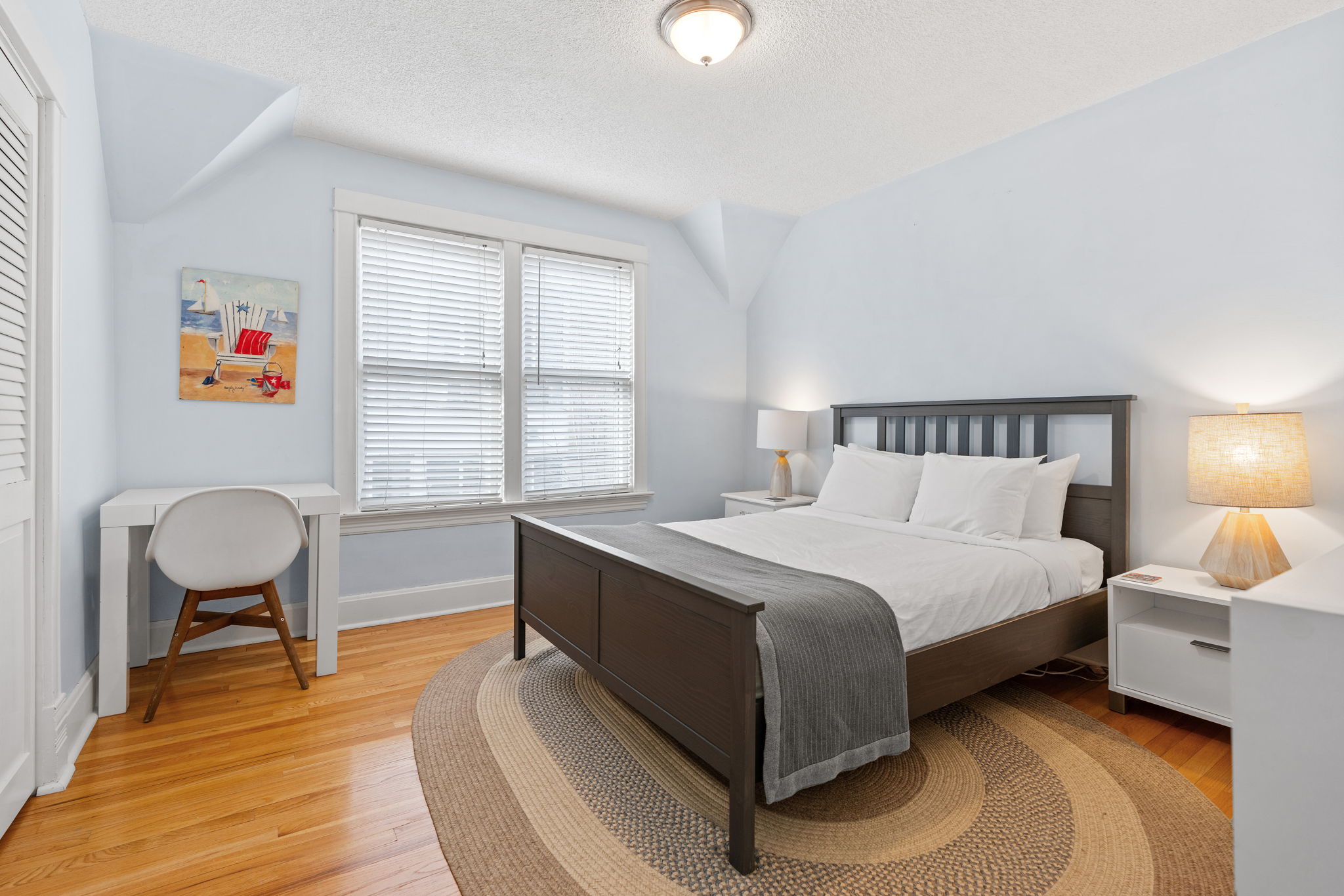 A serene bedroom with a modern bed, warm lighting, and beach-themed decor.