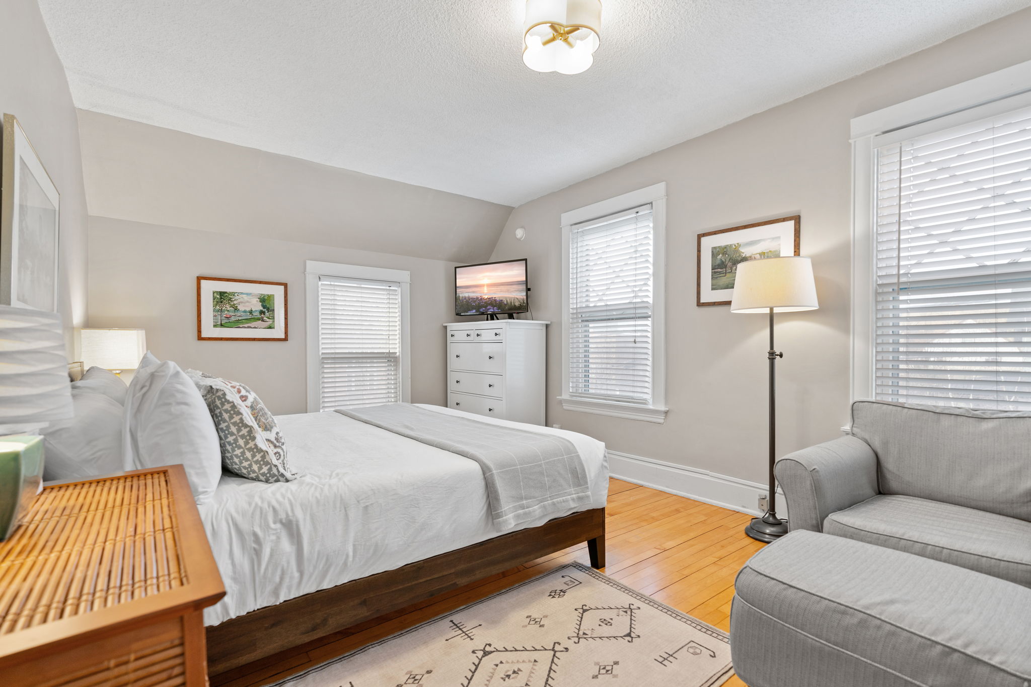 A cozy and well-decorated bedroom featuring soft tones and natural light.