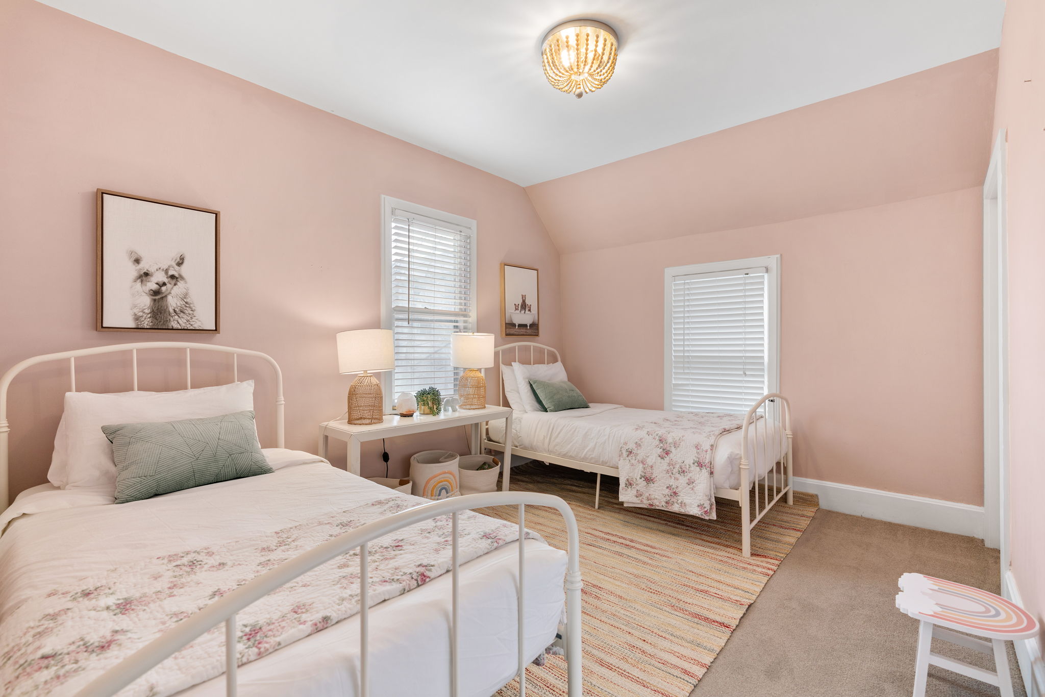 A charming pastel bedroom featuring two beds with floral decor and warm lighting.