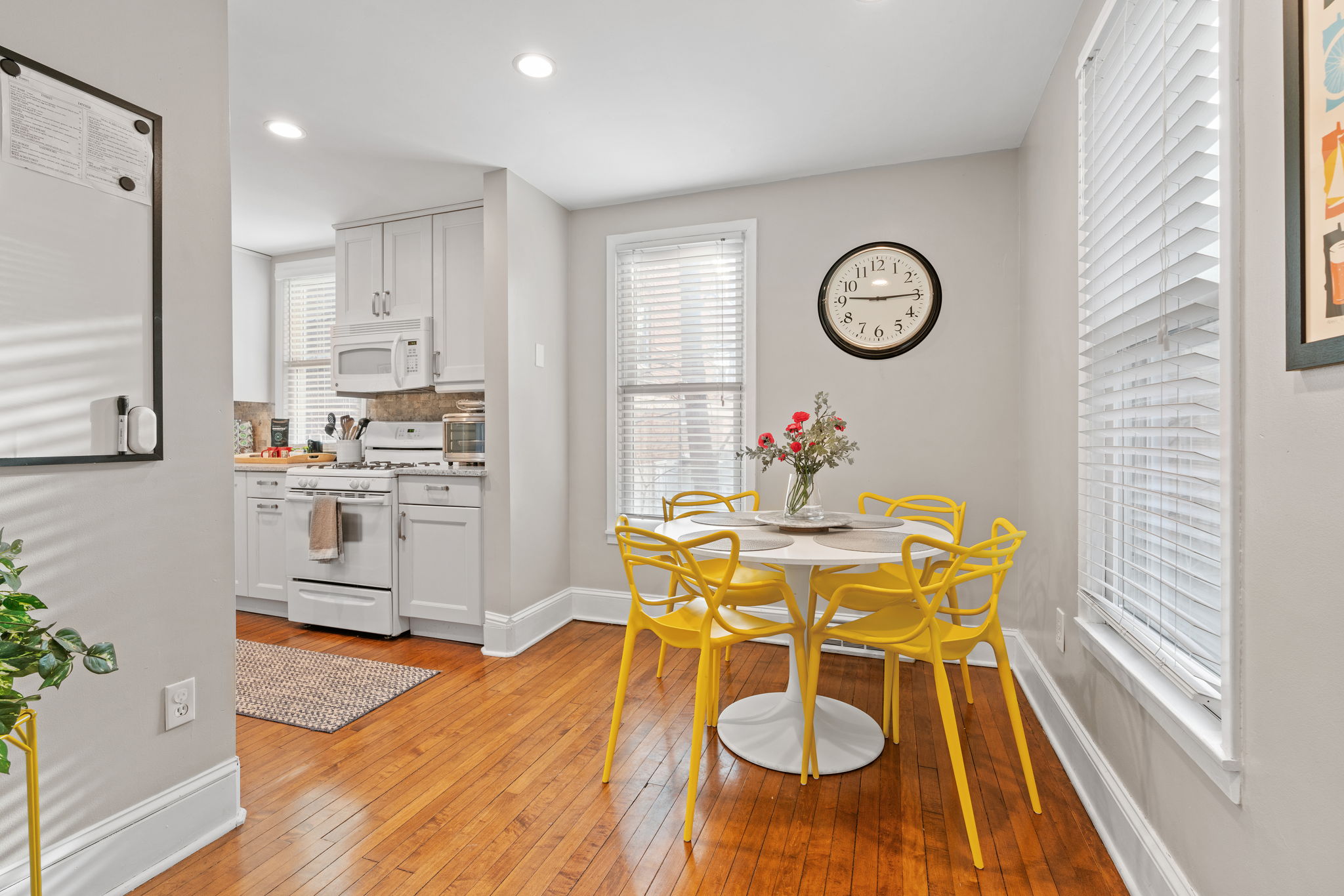 A modern kitchen area with yellow chairs and a floral centerpiece.