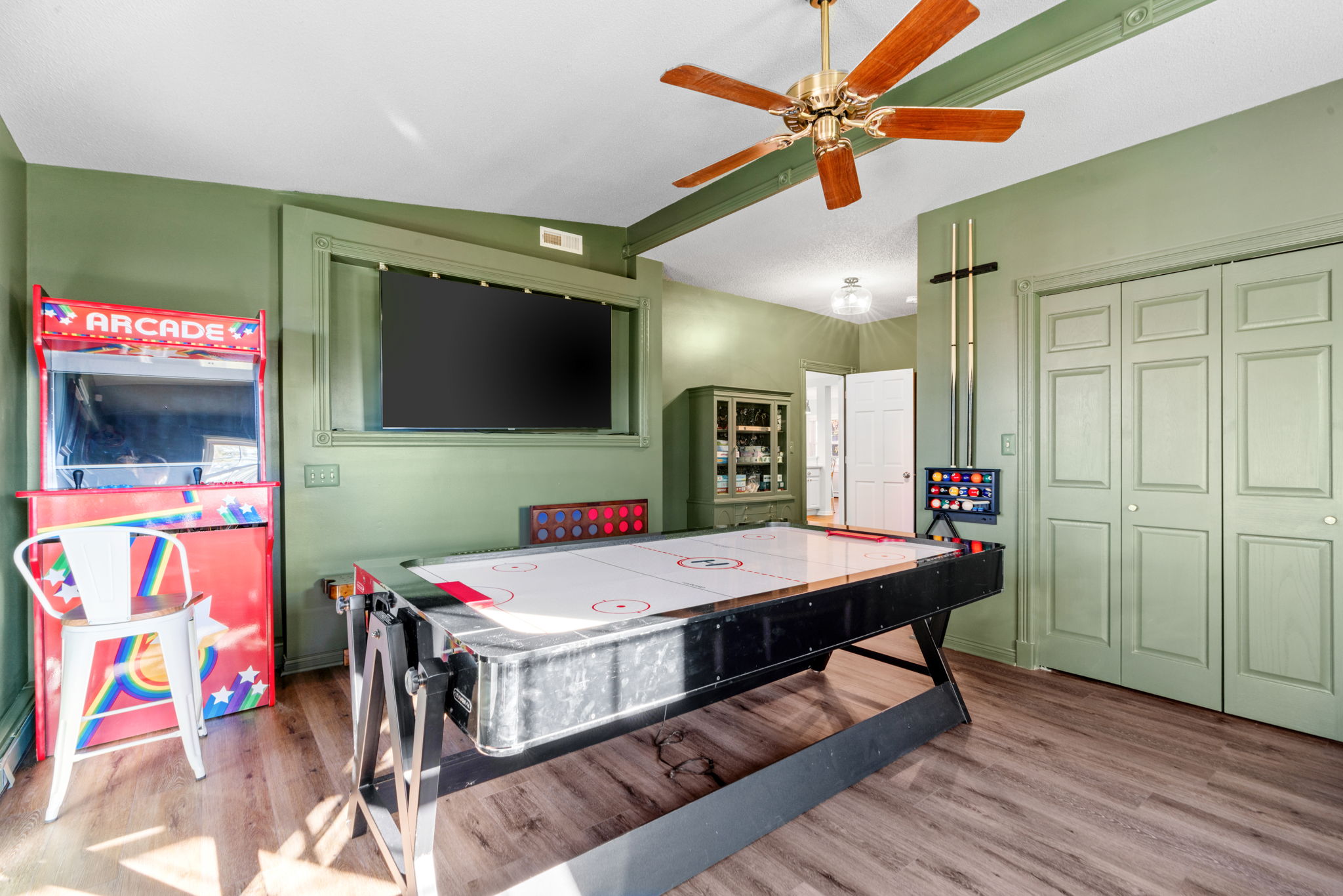 A vibrant game room featuring an air hockey table and arcade cabinet.