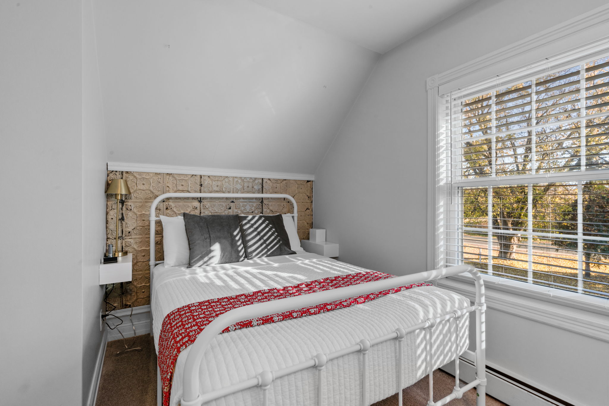 A cozy bedroom featuring a metal bed frame and unique textured wall.