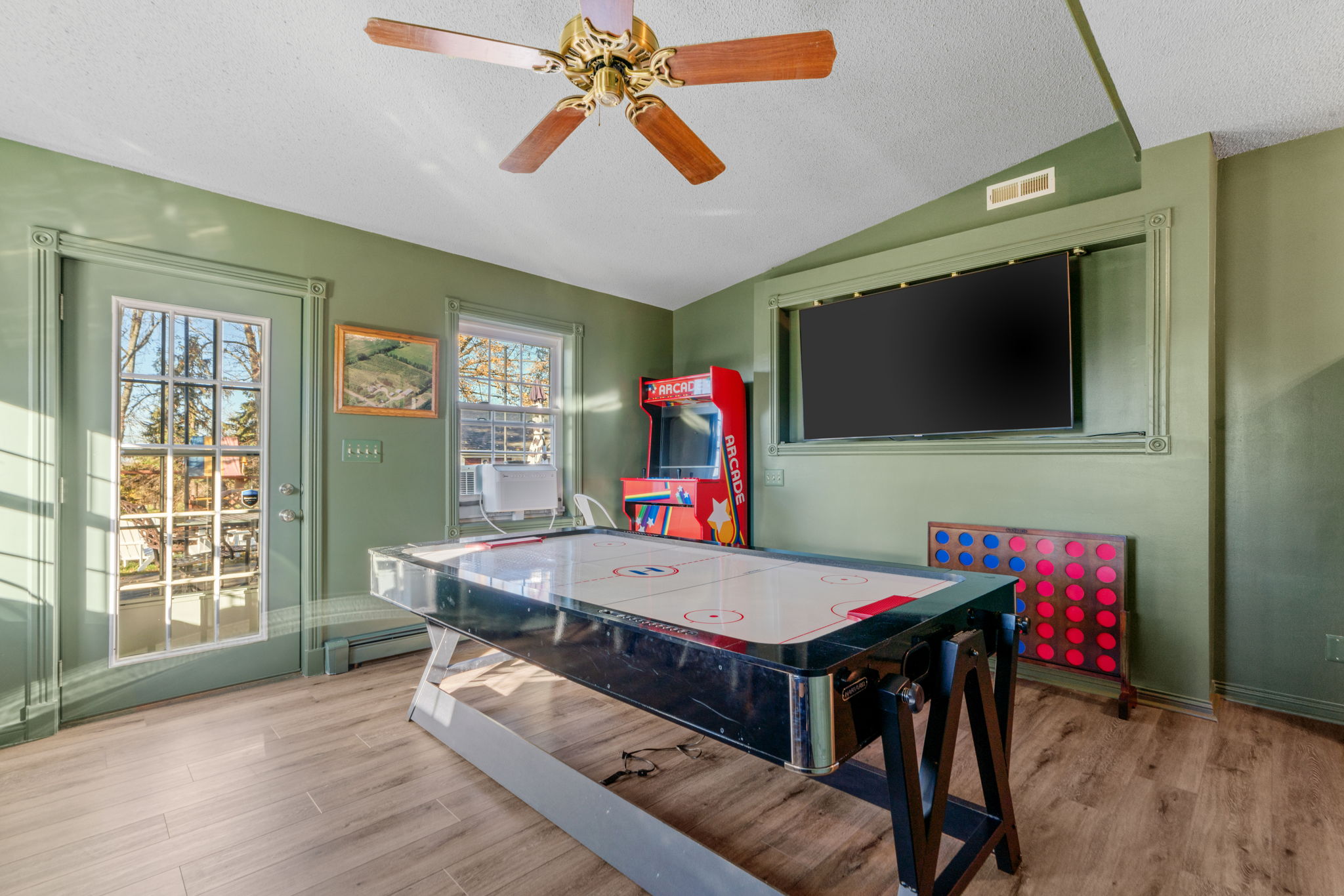A vibrant recreation room featuring an air hockey table, arcade game, and scenic views.