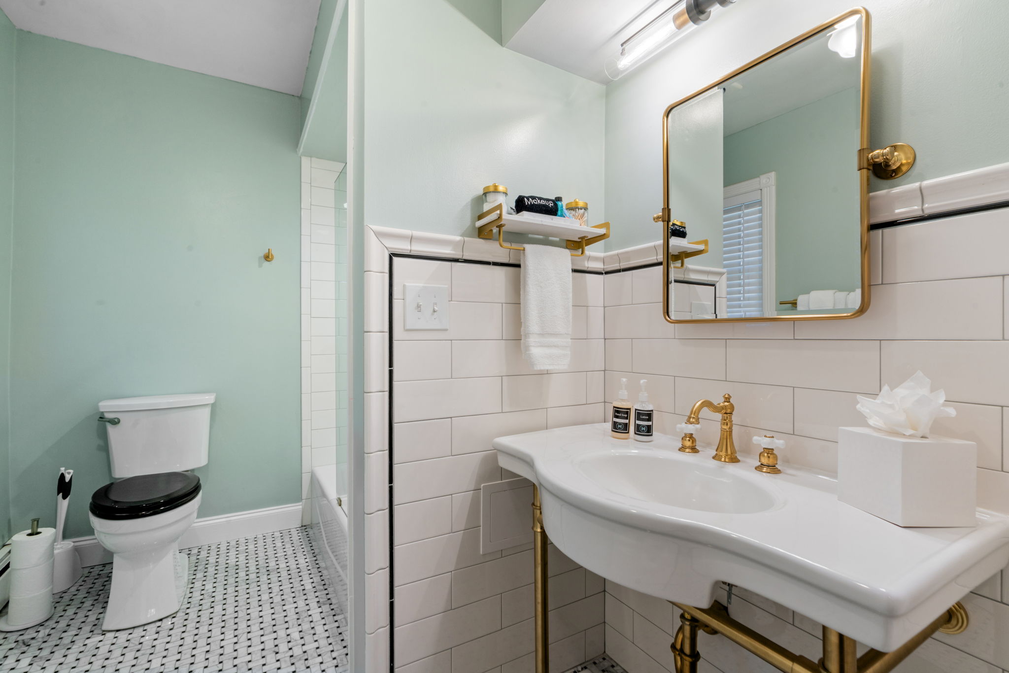 A stylish bathroom featuring mint green walls and elegant gold accents.