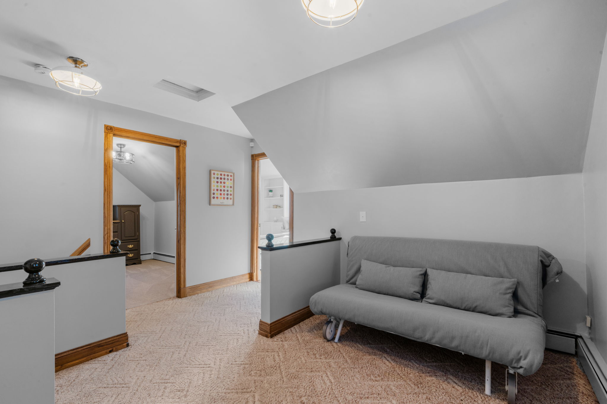 A cozy attic nook featuring a gray futon and colorful artwork.