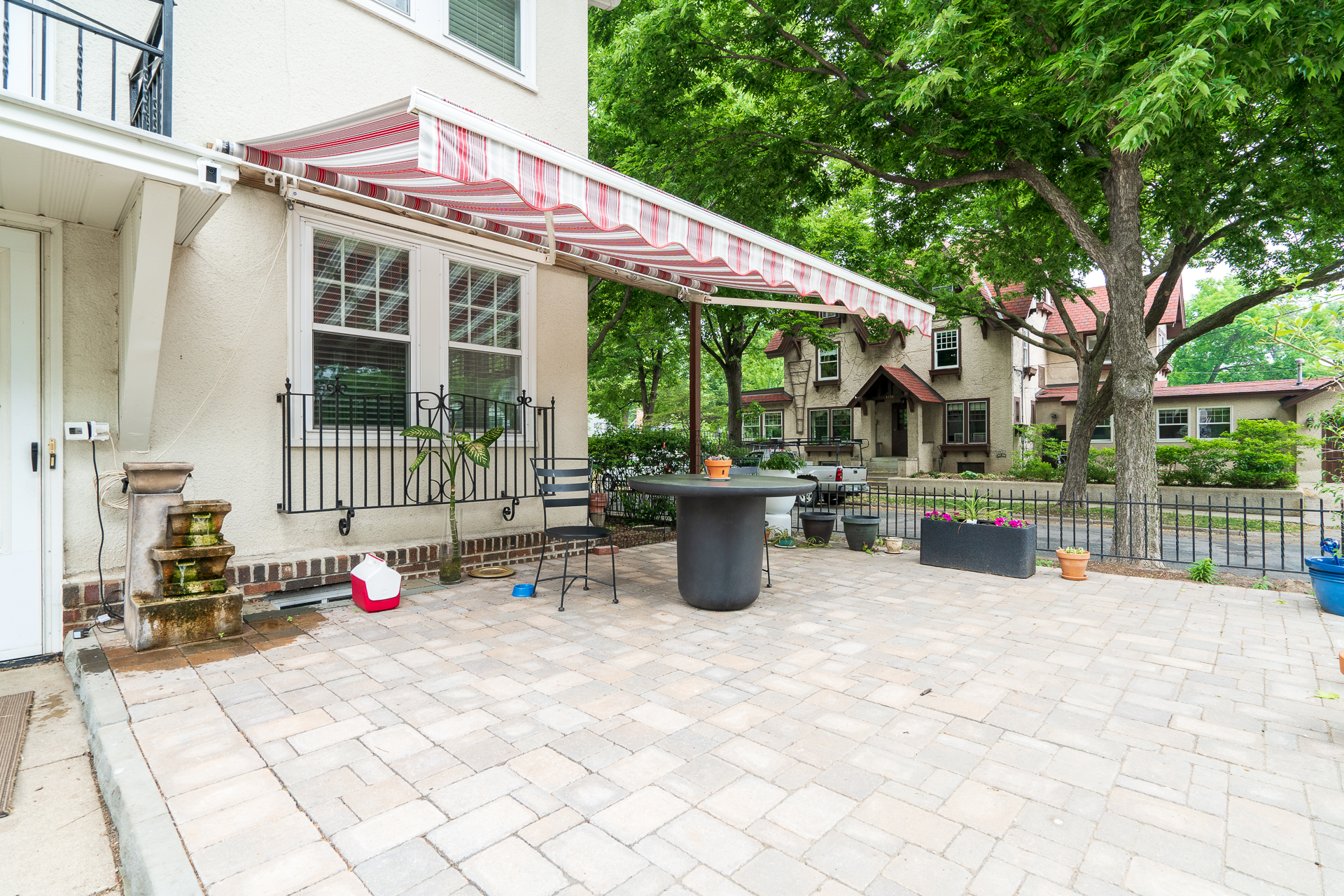 A cozy outdoor patio area with a striped awning and decorative plants.