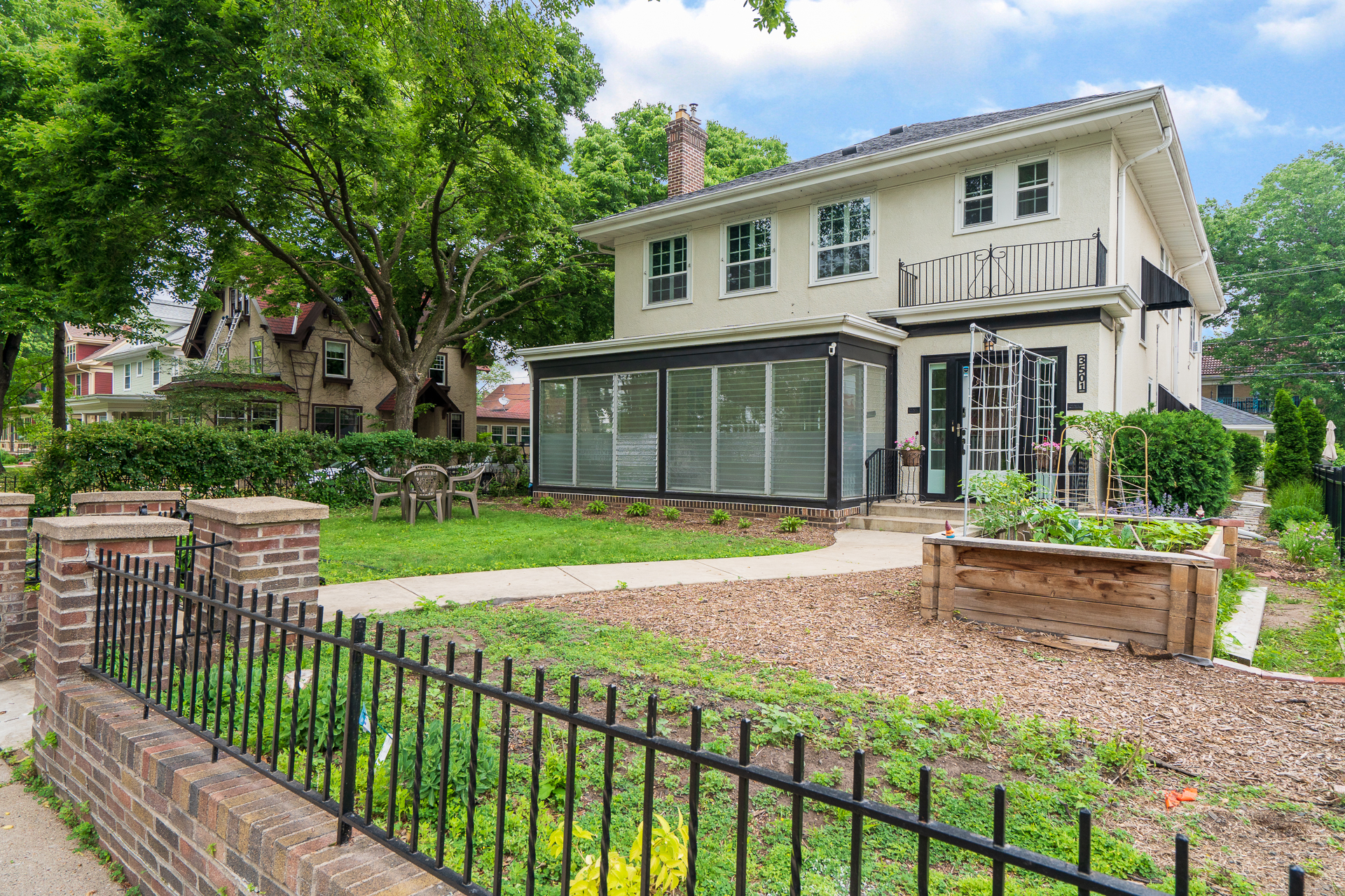 A charming two-story house with a beautiful garden and patio area.