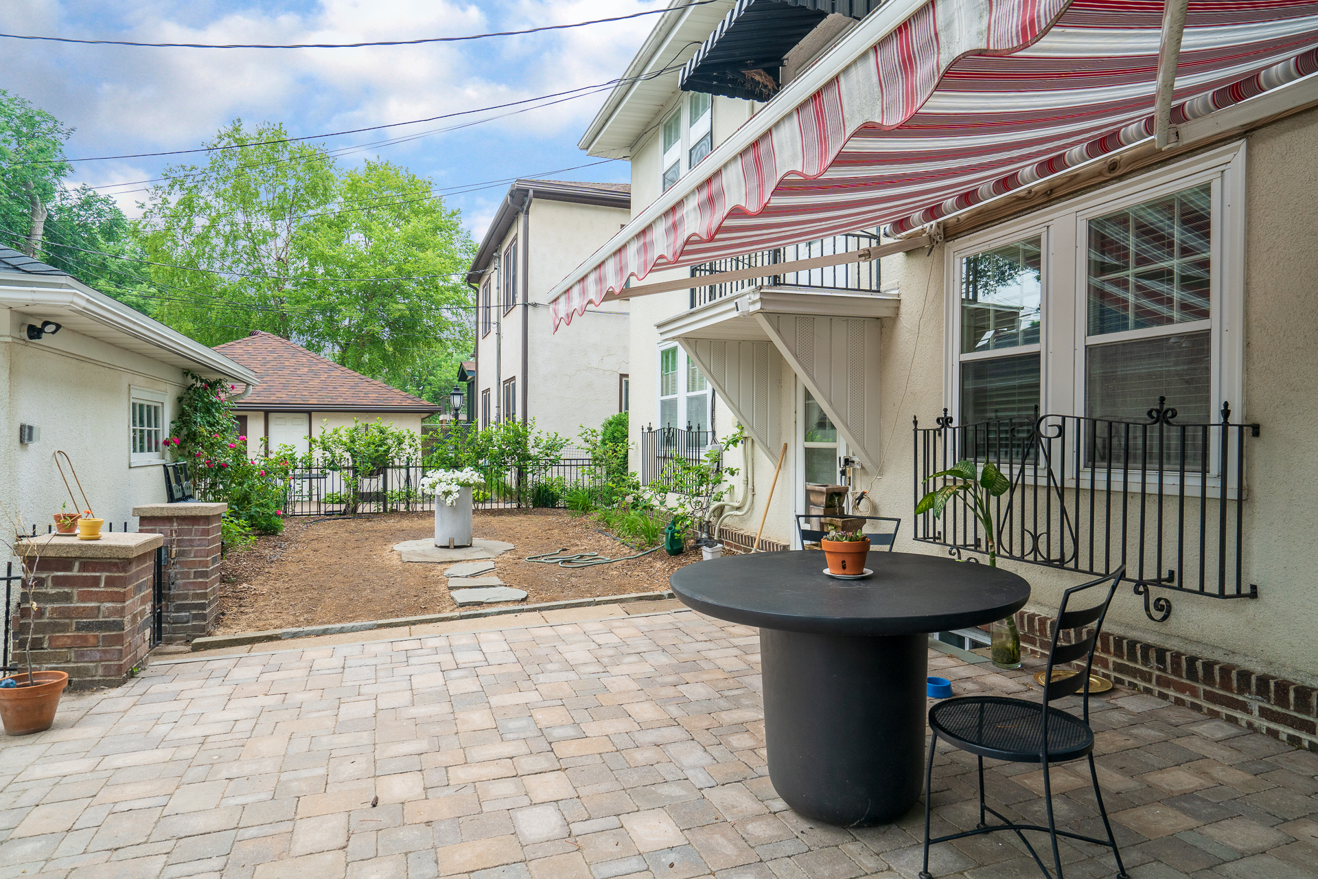 A serene patio area with a round table and lush greenery.
