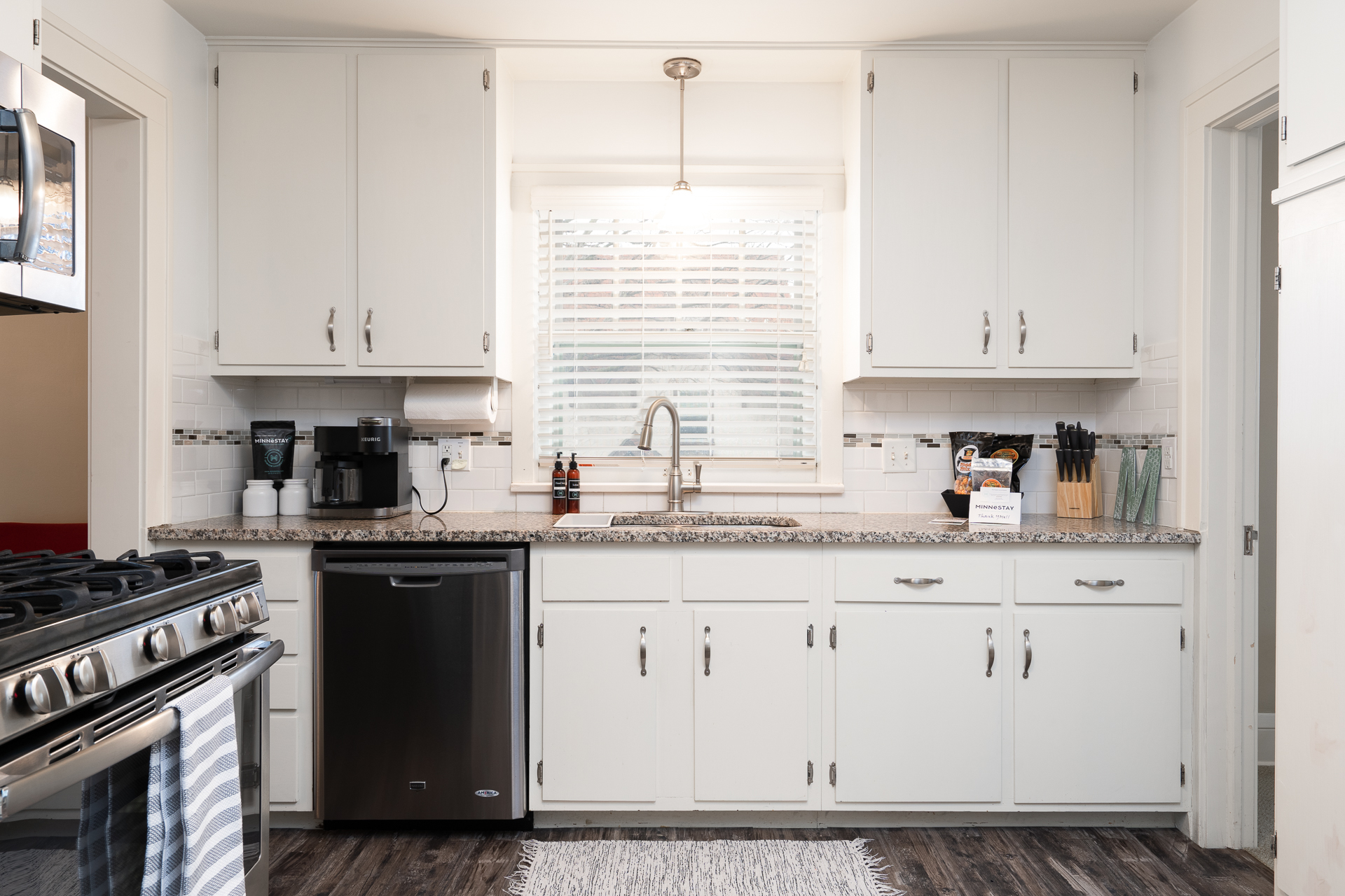 Modern kitchen with white cabinetry and granite countertops.