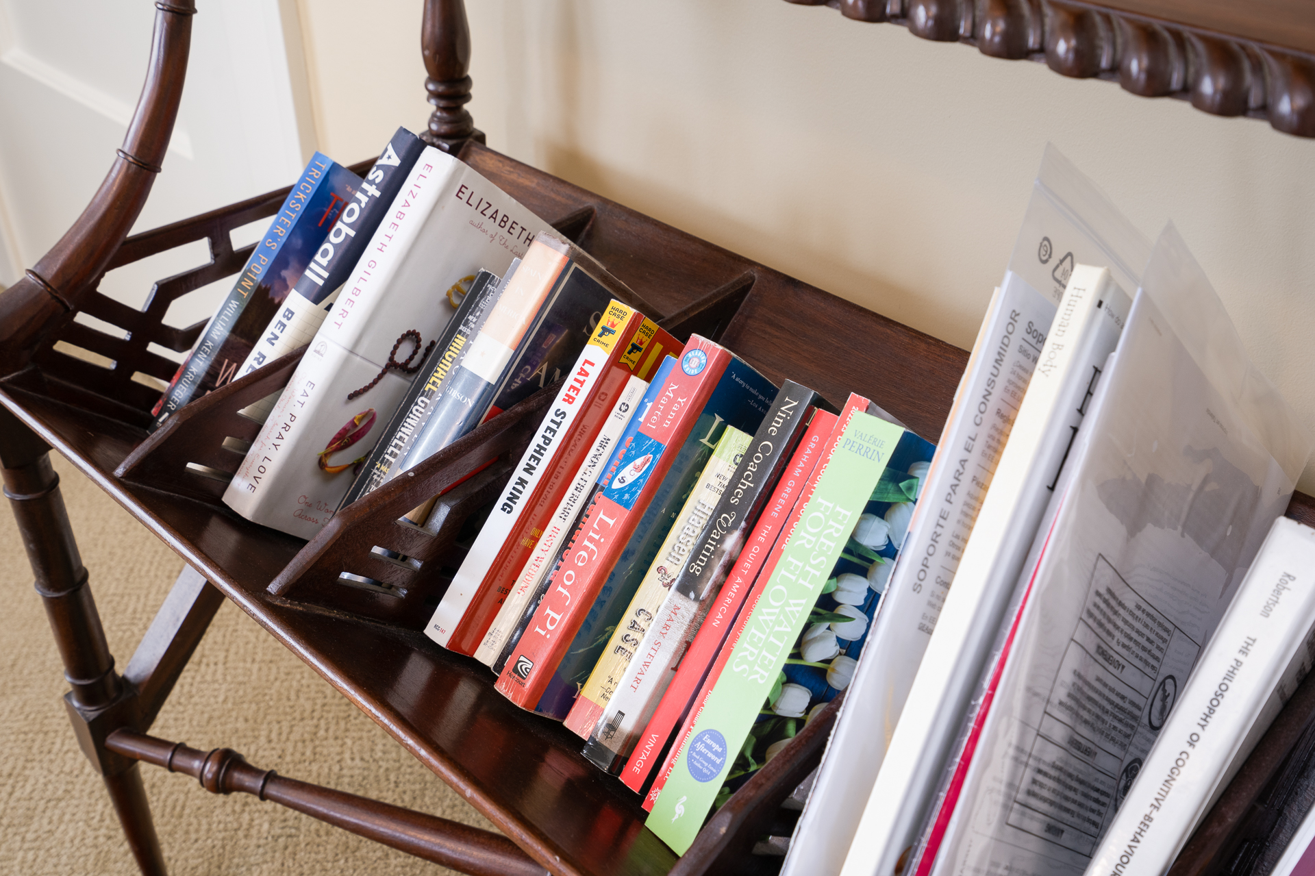 A beautifully organized wooden book rack filled with a variety of books and magazines.