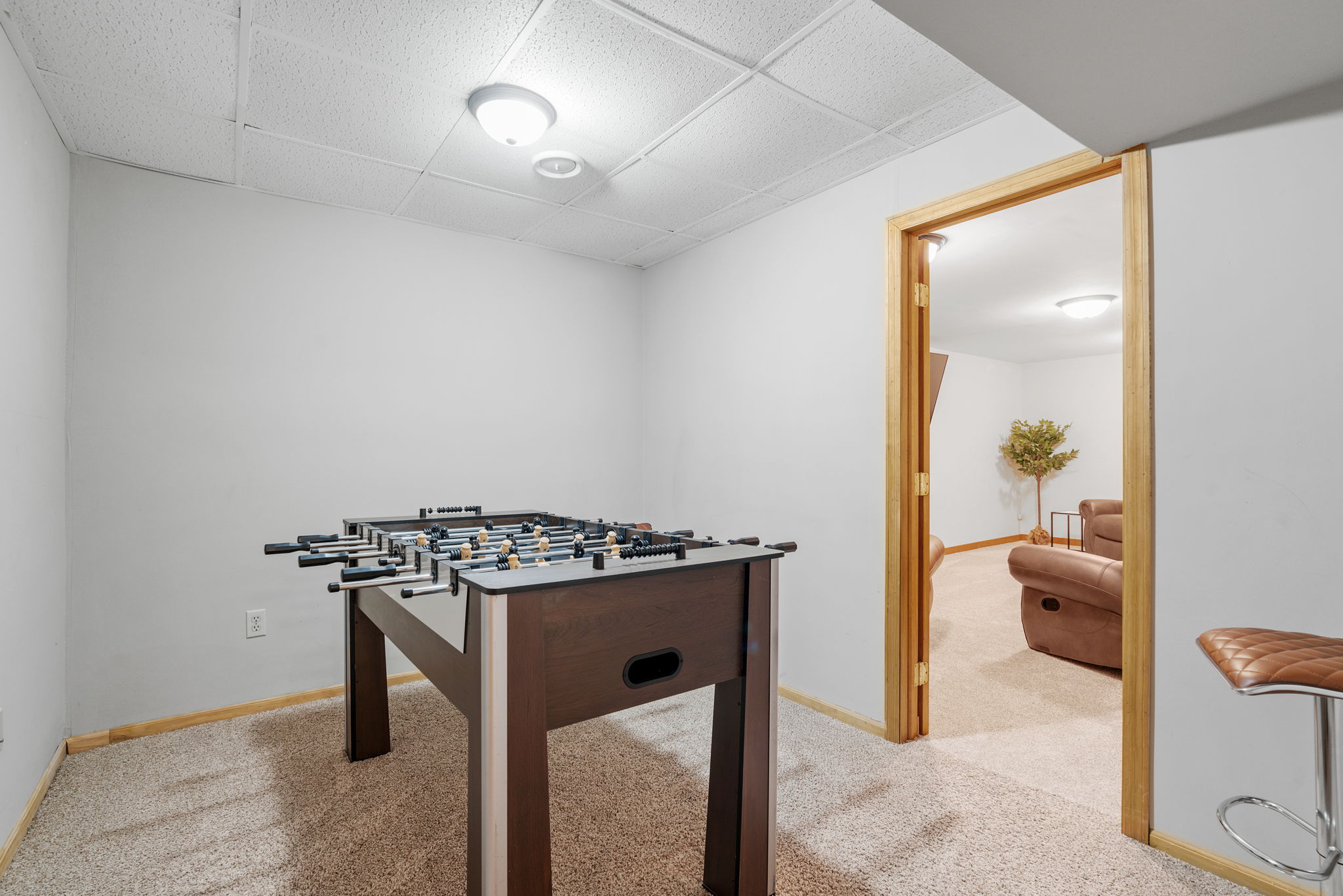 A cozy basement game room featuring a foosball table and comfortable seating area.