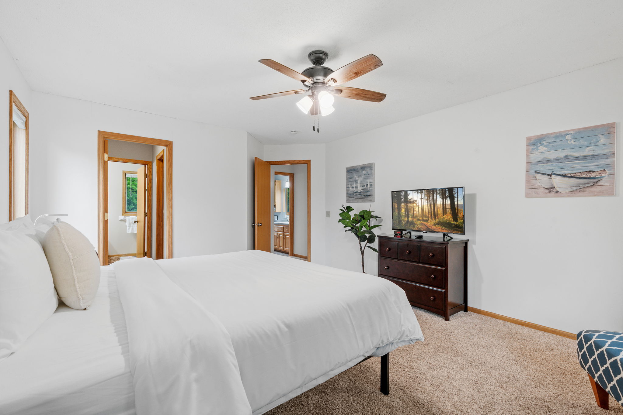 A cozy and well-decorated bedroom featuring a neatly made bed and a television.