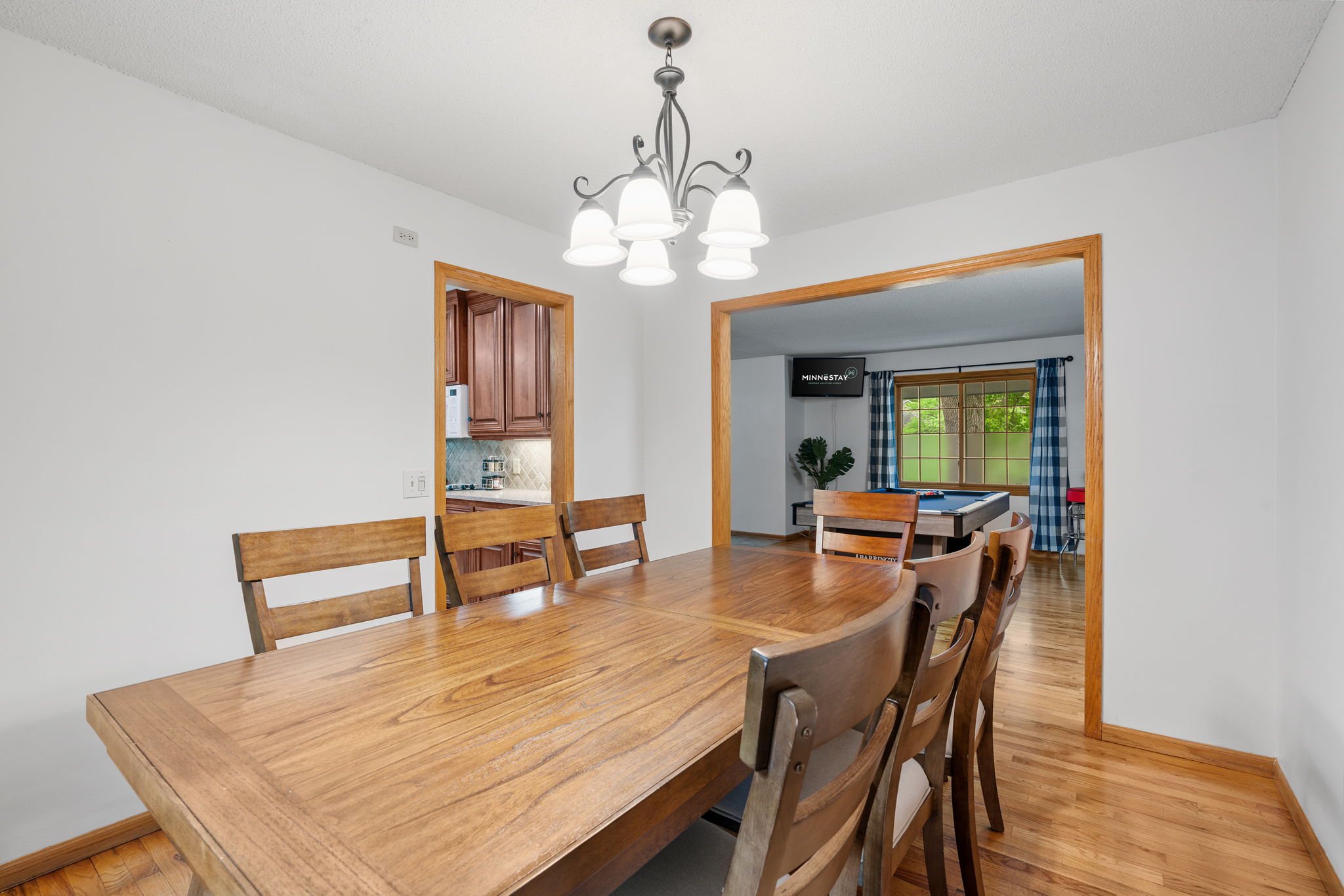 A cozy dining area featuring a large wooden table and stylish chandelier.