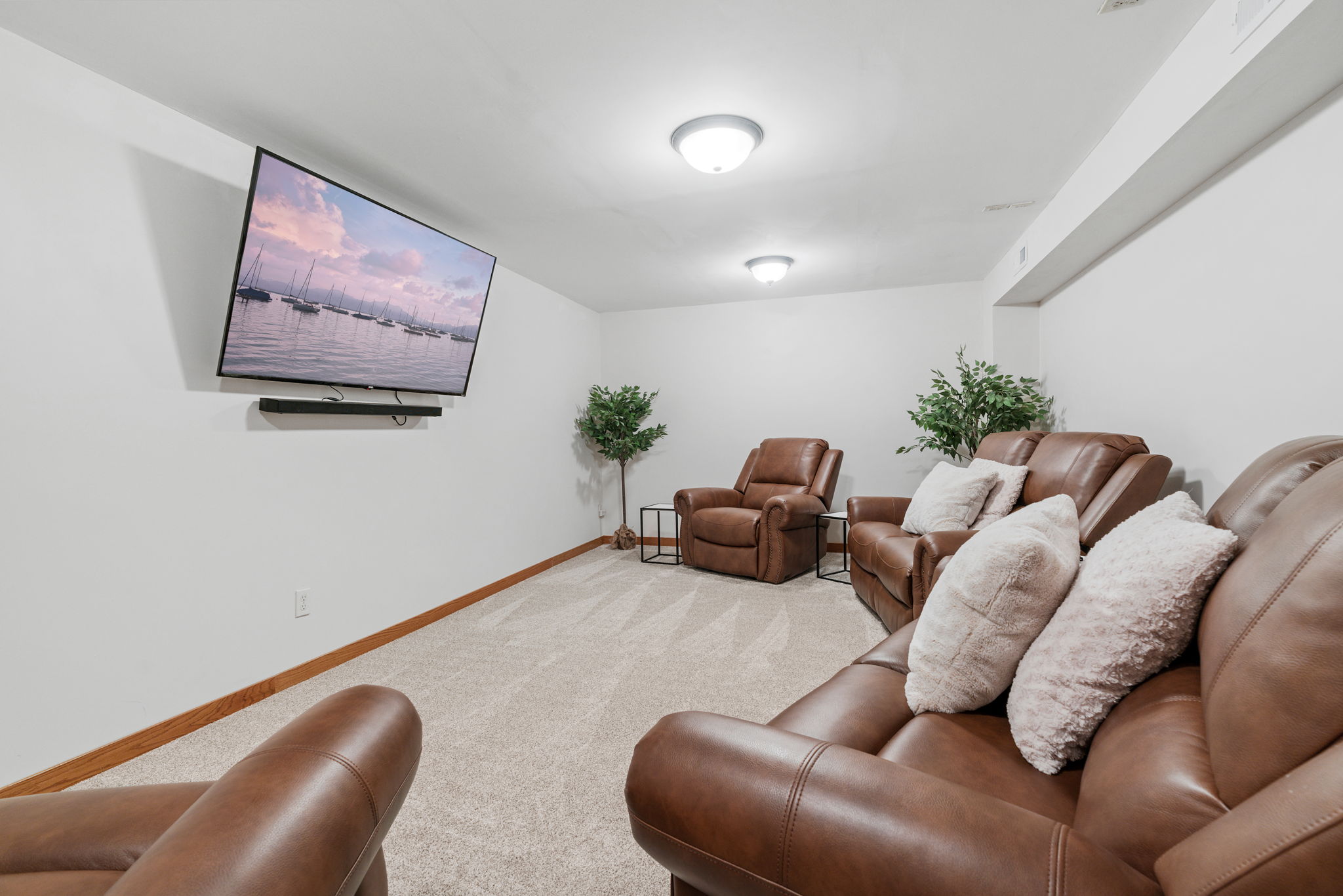 Cozy basement entertainment room with leather recliners and a mounted TV.