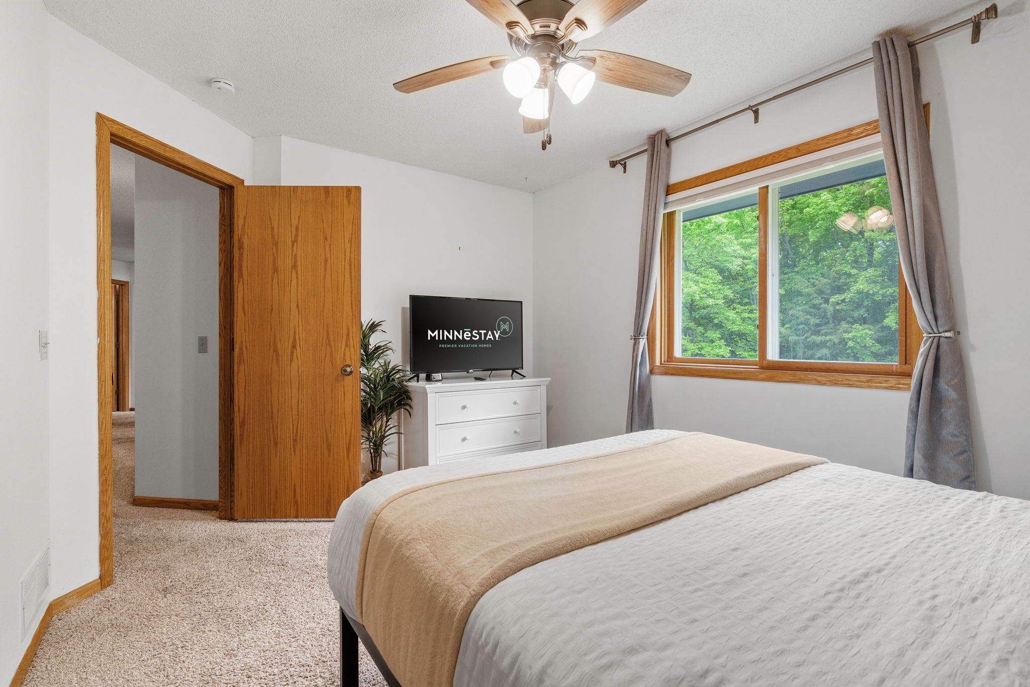 A cozy bedroom with modern decor and a lovely view of greenery.