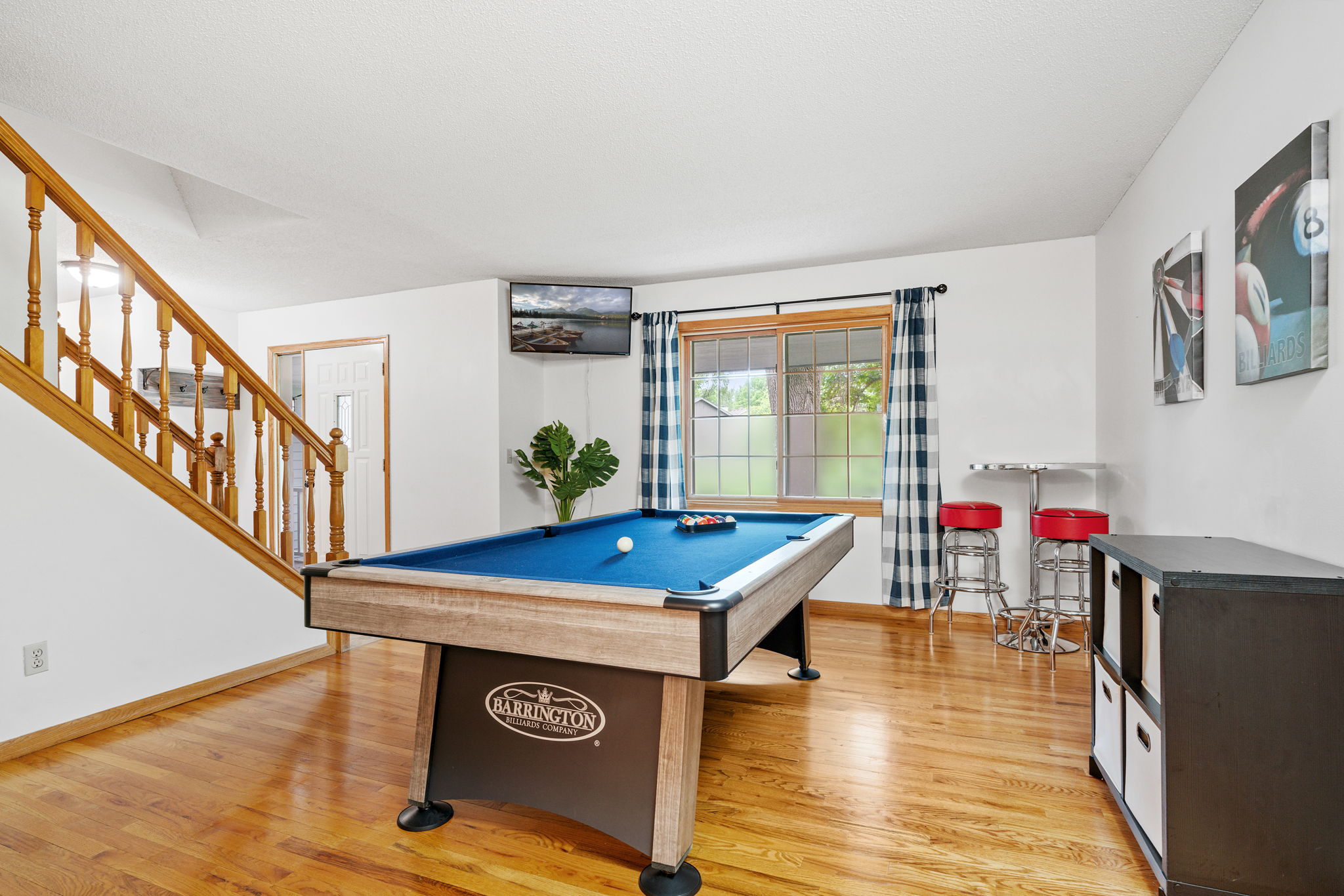 A cozy game room featuring a billiard table, stylish bar seating, and a scenic view.