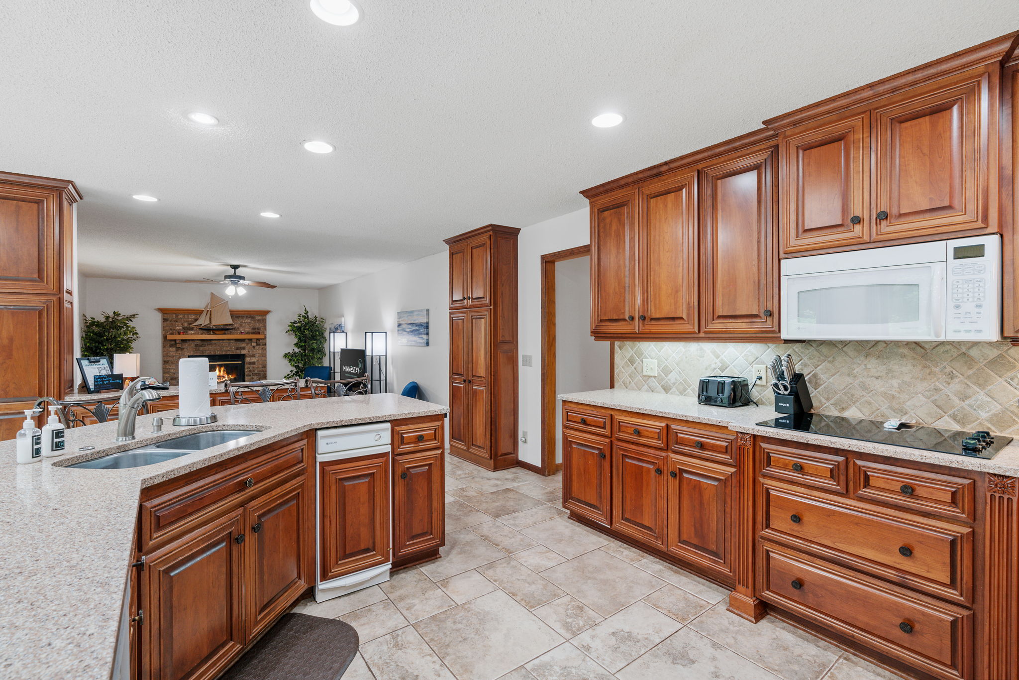 Warm wooden cabinetry defines this inviting kitchen, featuring an integrated living area with a cozy fireplace.