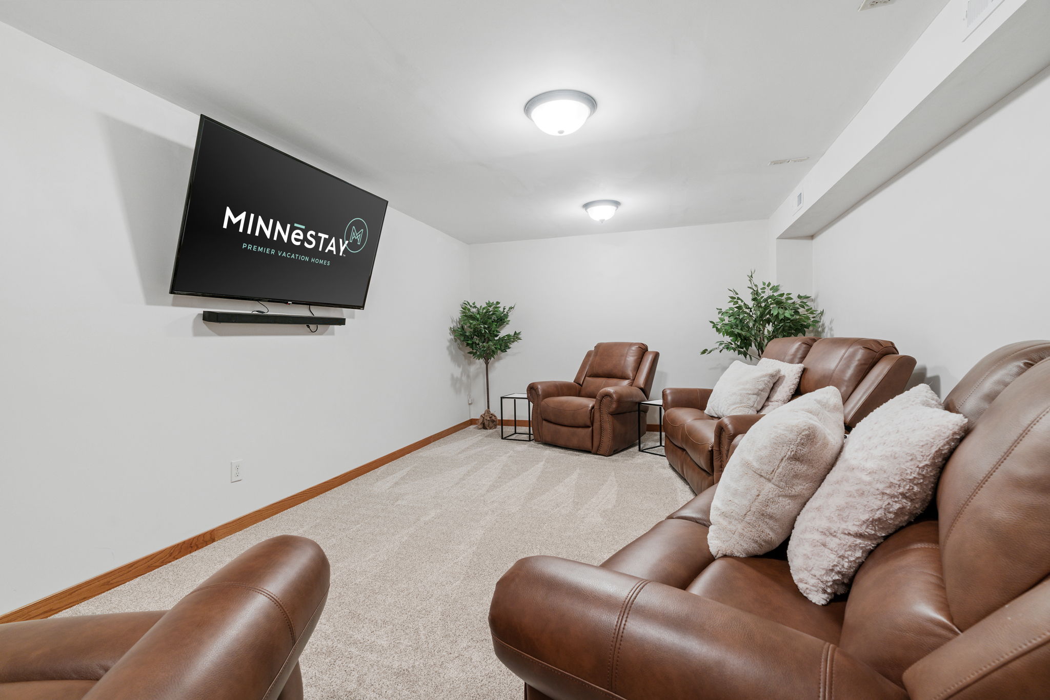 A modern basement lounge featuring leather recliners and a wall-mounted TV.