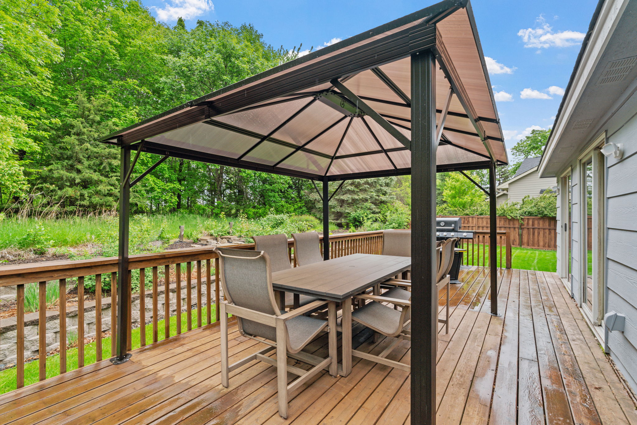 A serene outdoor deck with a gazebo and dining area surrounded by greenery.
