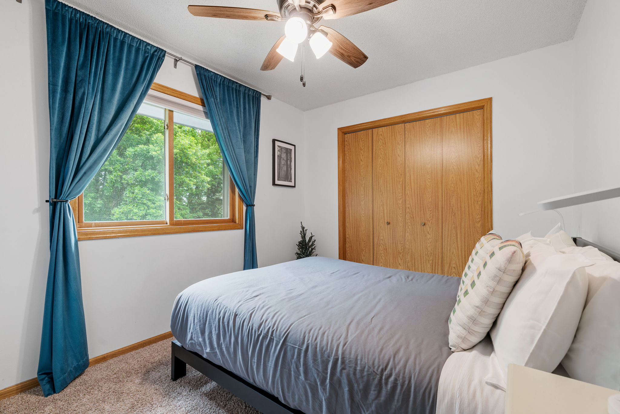 A tranquil bedroom featuring light blue bedding and teal curtains.