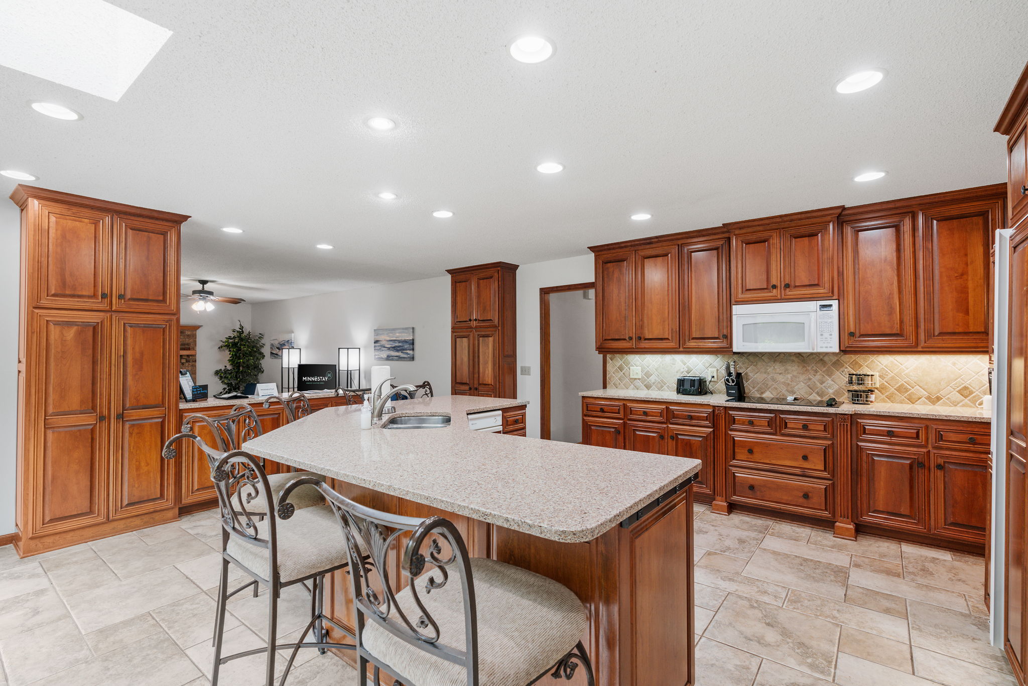 An elegant kitchen featuring a large central island and rich wooden cabinetry.