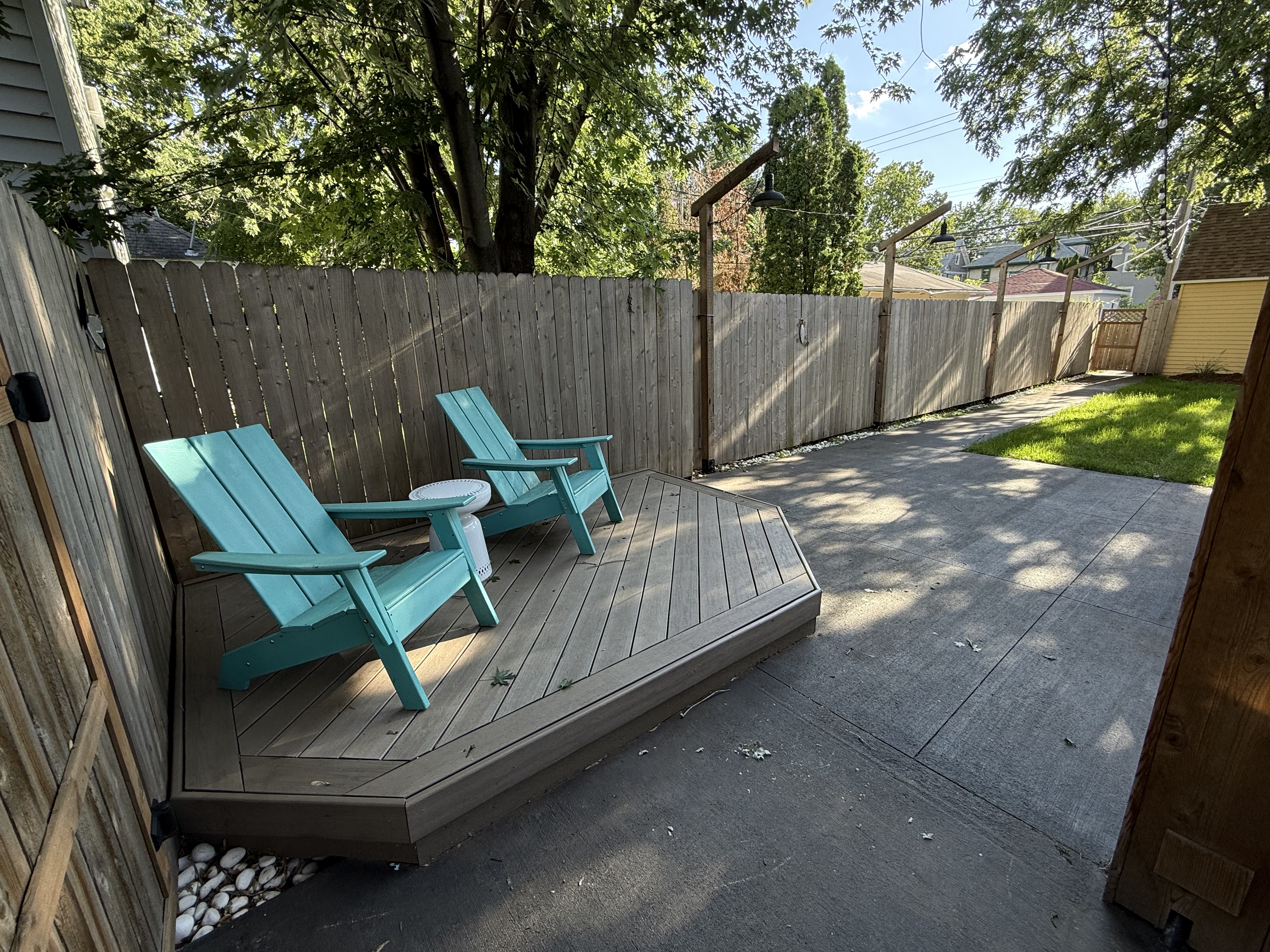 A tranquil backyard space with aqua blue Adirondack chairs and a cozy wooden deck.
