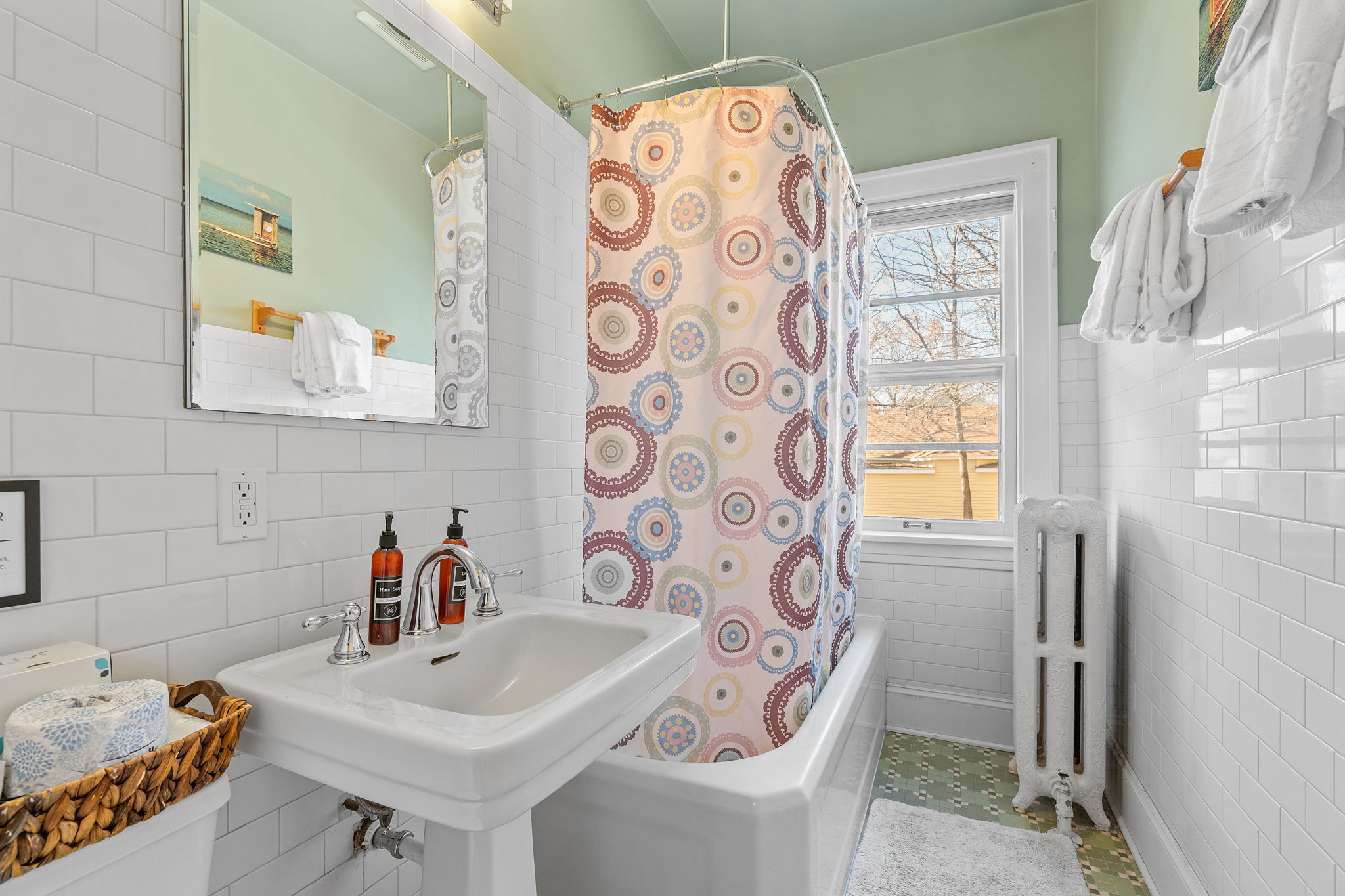 A charming bathroom featuring a colorful shower curtain and vintage decor.