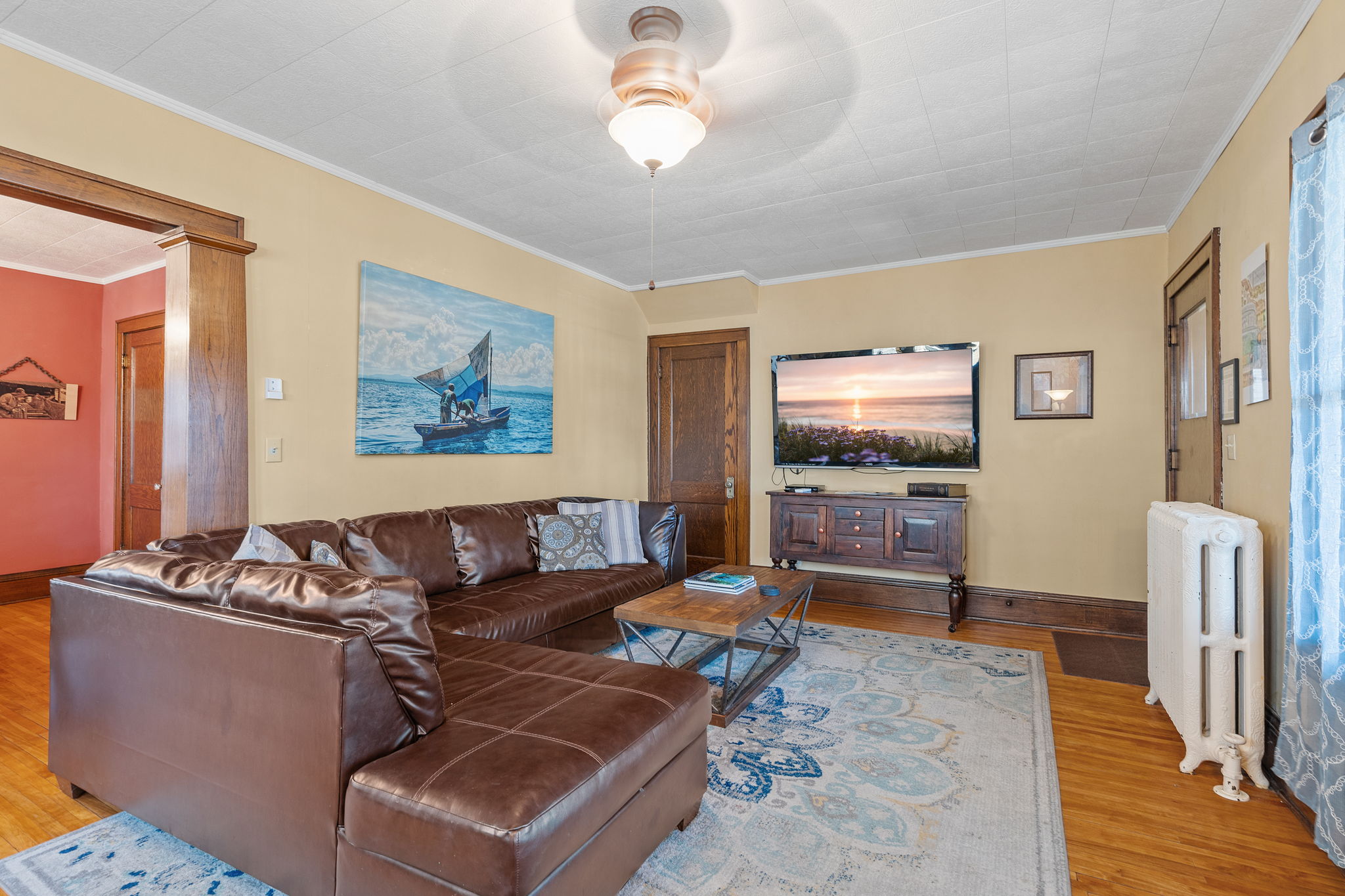 A cozy living room with a leather sectional, art, and television.