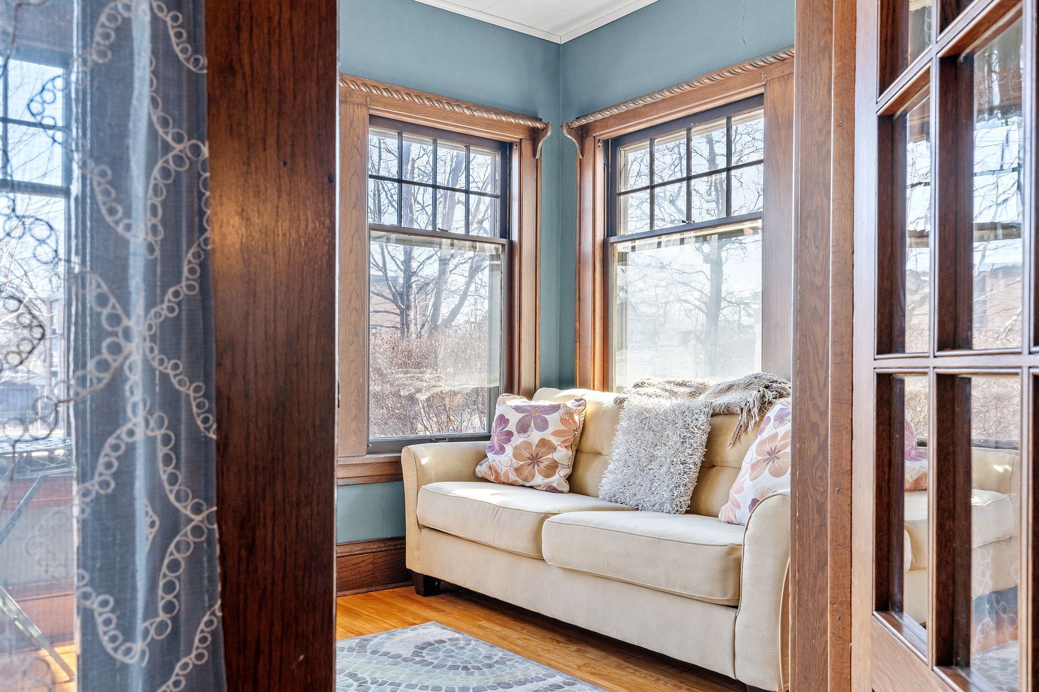 A cozy sitting area with light from large windows and a decorative couch.