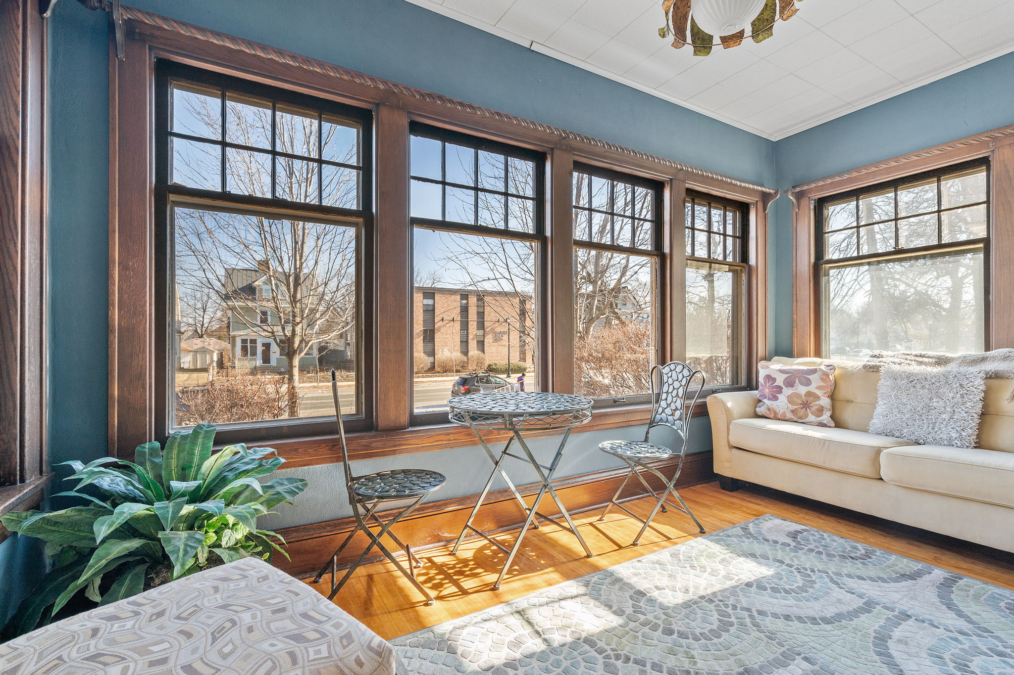 Cozy sunroom with large windows, a small table, and a sofa.